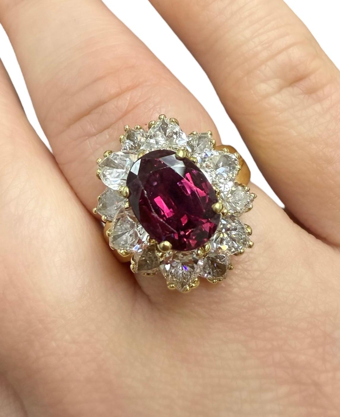 This beautifully classic cocktail ring boasts a bright oval brilliant cut ruby measuring 9.83 x 7.49 x 4.88 mm and weighing approximately 3.09 carats, surrounded by 12 pear shaped diamonds weighing approximately 4.50 carats total. Made with