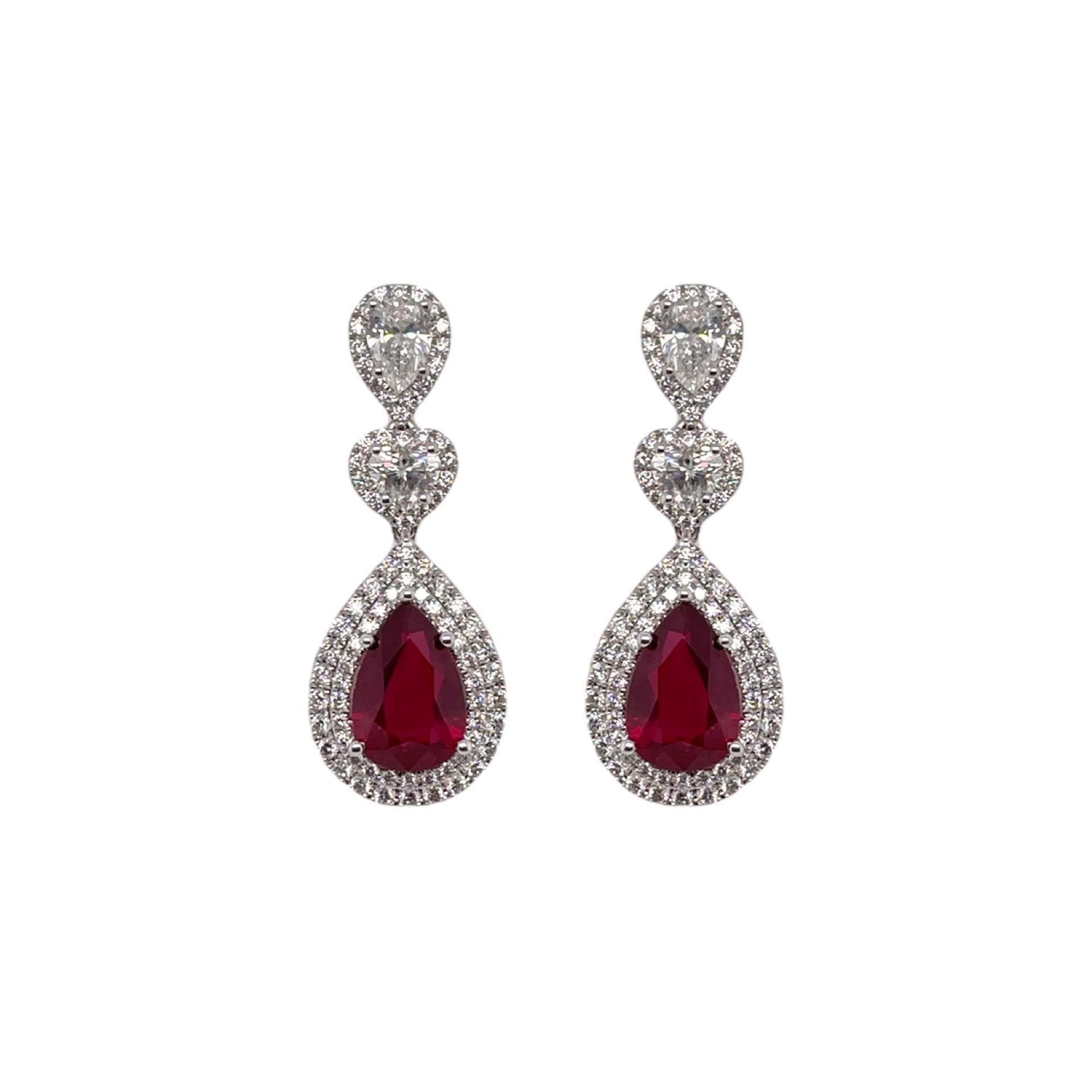 Earrings contain 2 finely matched GIA certified pear shaped rubies, 4.62tcw. Gemstones are surrounded by a double row of round brilliant diamonds and accented by a pear and heart shape diamond drop, 2.00tcw. Diamonds are colorless and VS2 in