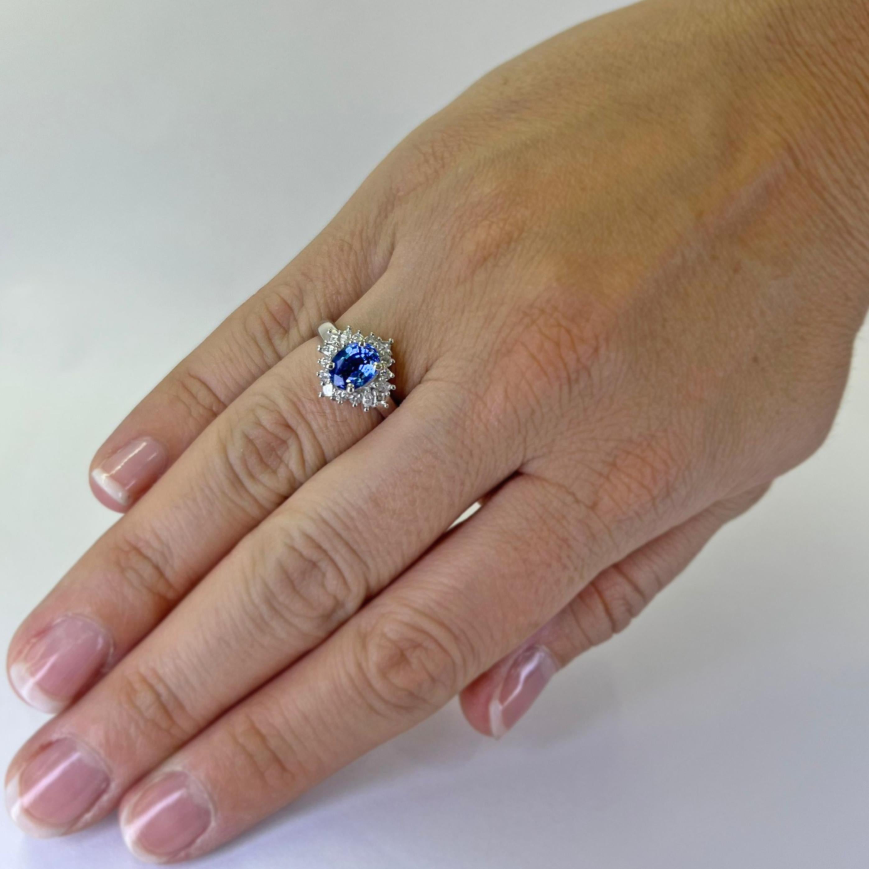 Platinum halo ring featuring a 1.31 carat oval Sri Lankan oval sapphire (GIA report #2239057238) surrounded by 0.34 carat total weight square emerald cut, round, and marquise cut diamonds of VS clarity and G/H color. Finger size 6. Includes One