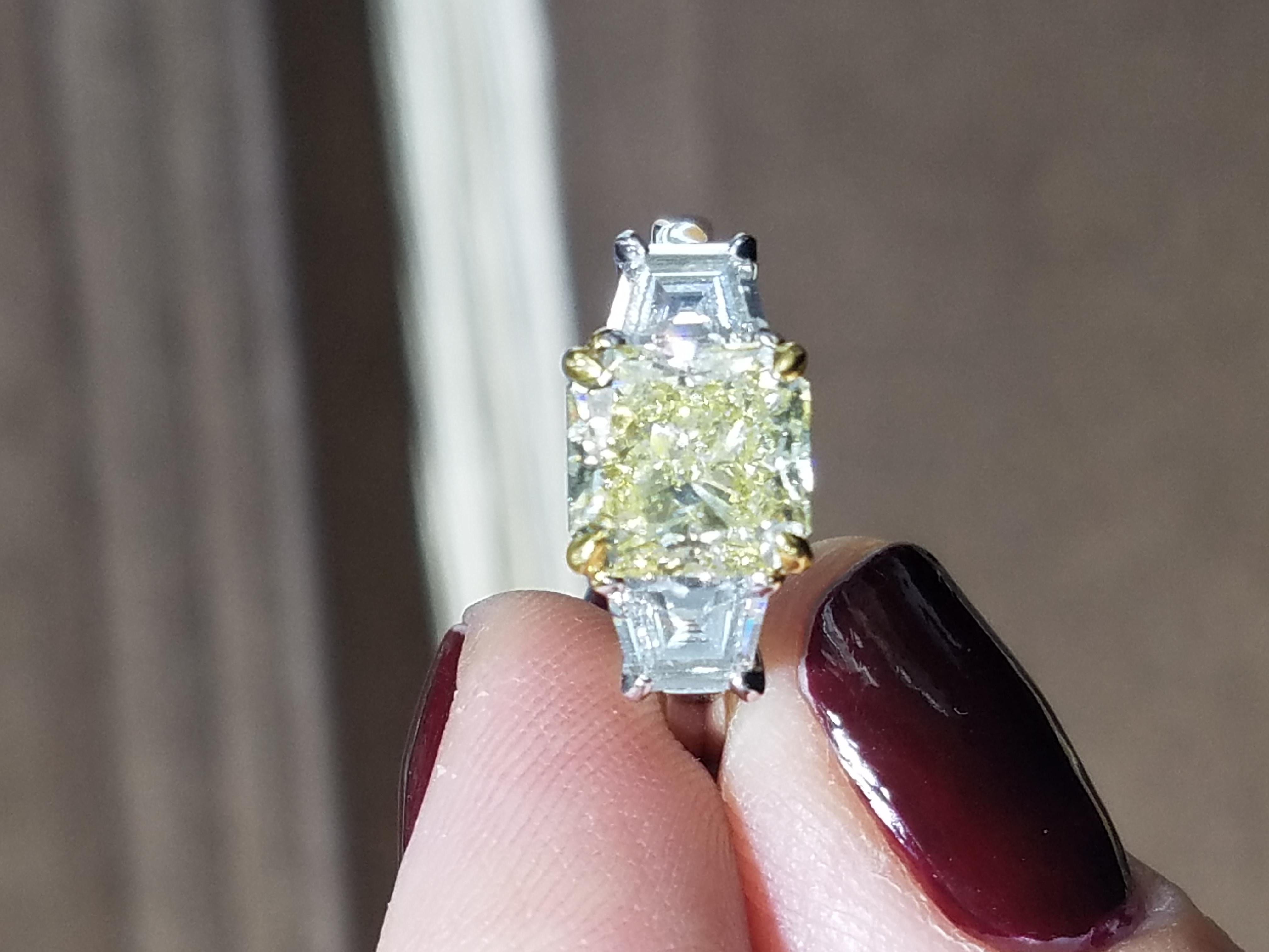 Fit for a princess! This unique three stone fancy yellow diamond engagement ring has to be seen! This ring is set with an amazing 3.03 carat Fancy Yellow Radiant Cut which will take her over the moon! Two side diamonds add another carat to the total
