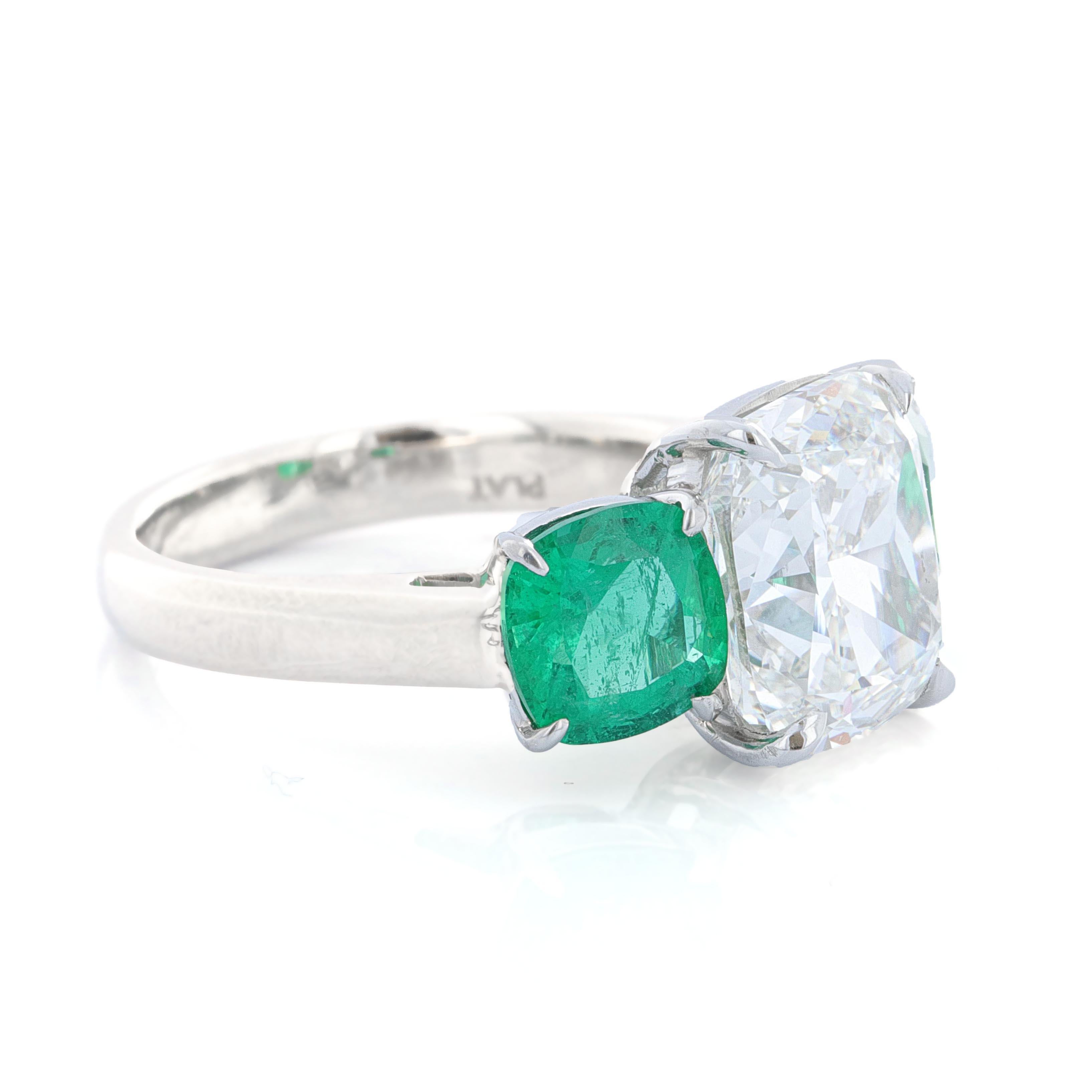 Platinum three stone diamond ring with cushion cut center and emerald side stone. The centerstone is GIA certified. It is a cushion cut modified brilliant weighing 4.73 carats. It is G color and VS1 clarity. The diamond measures 10.00 x 8.91 x