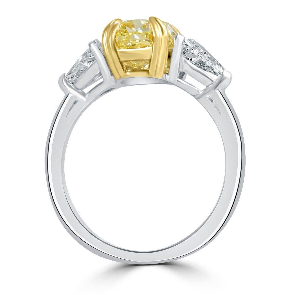Three stone diamond engagement ring features a 3.10 carat GIA certified oval cut light yellow (U to V Range) diamond center embraced between 2 trillion cut colorless diamonds. Handcrafted in 18k multi tone gold and completed with a high polish