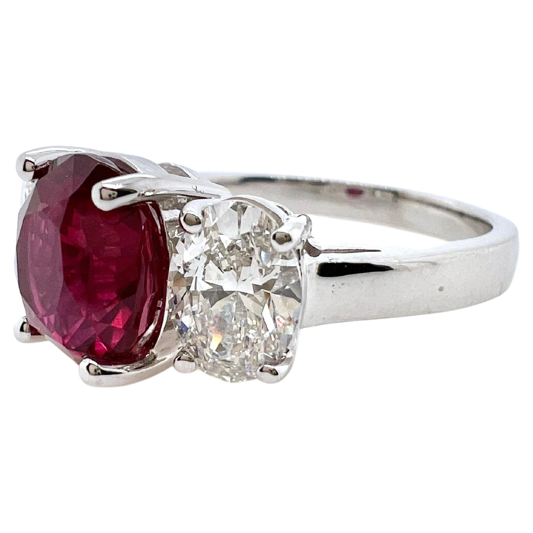 This classic three stones ring will be cherished for generations to come.  The center ruby is GIA certified, unheated 3.09 cts oval cut. It is accompanied by two oval diamonds, both GIA certified, F color, VS1 and VS2 clarity.  The gorgeous ruby has