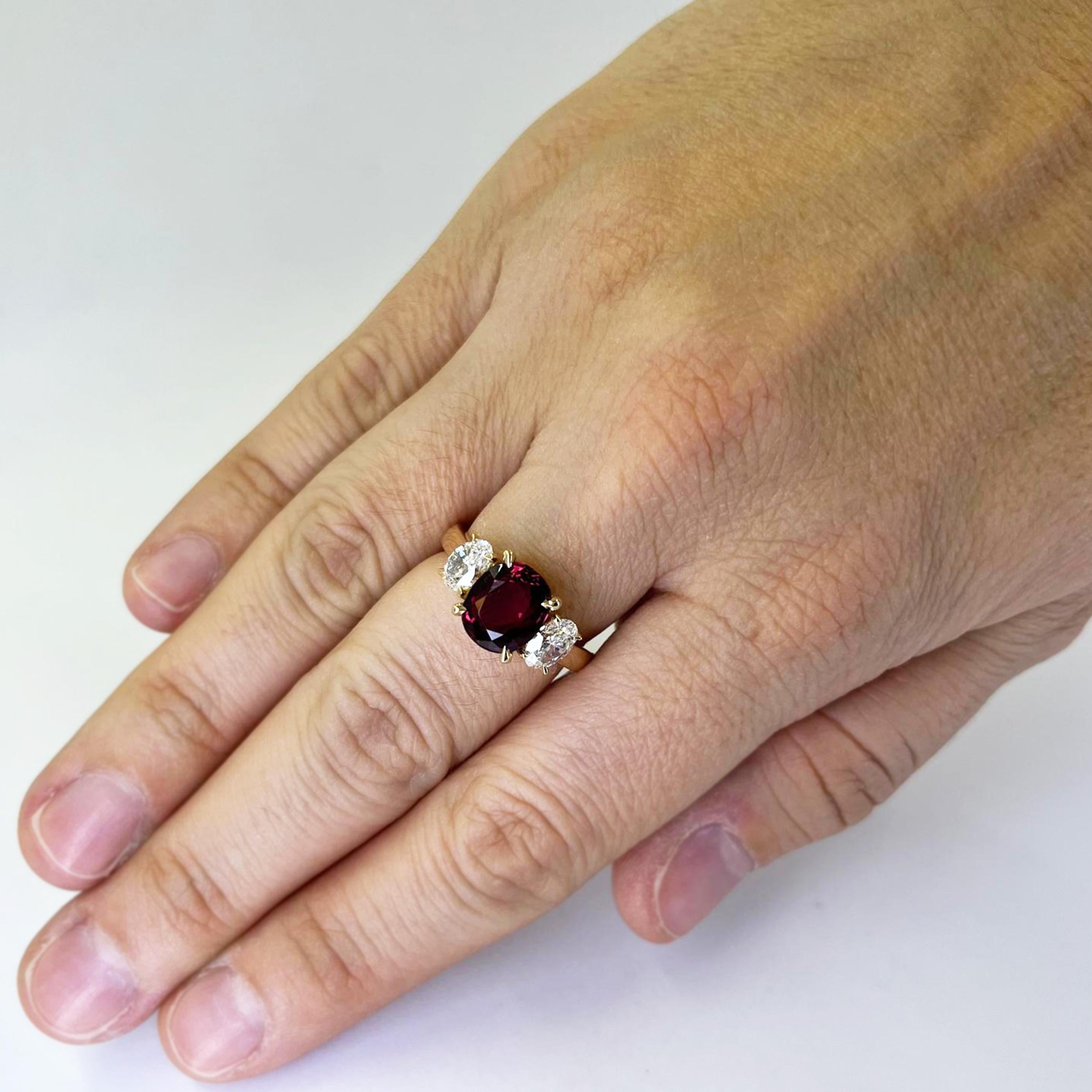 Bague en or jaune 18 carats composée de trois pierres, dont un rubis thaïlandais non chauffé de 3,40 carats de taille ovale avec rapport GIA 2235346604, accentué par deux diamants de taille ovale de couleur G et de pureté VS2 (rapports GIA