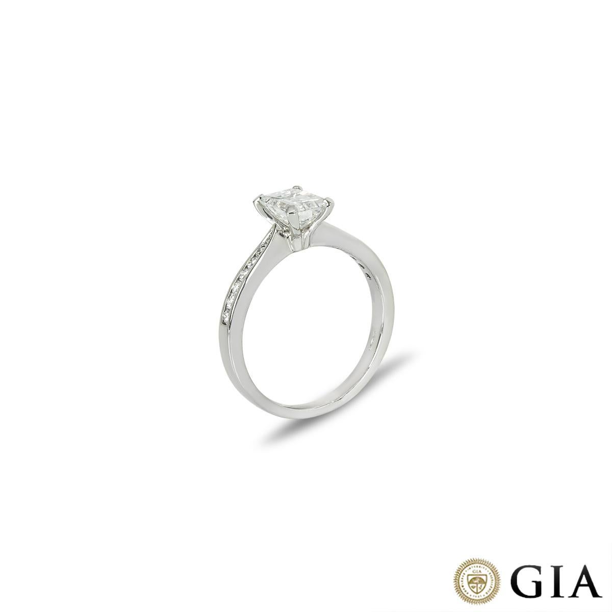 Magnifique bague de fiançailles en or blanc 18 carats, ornée de diamants. Un diamant de taille émeraude pesant 0,95ct, de couleur D et de pureté VS1, est serti au centre dans une monture classique à quatre griffes. Les épaules sont ornées de 14
