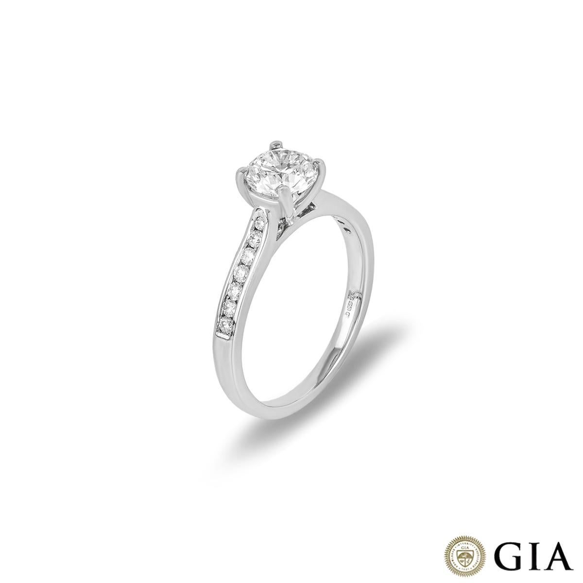 A beautiful 18k white gold diamond engagement ring. The central round brilliant cut diamond is set in a four claw mount, weighing 0.90ct, H colour and VS1 clarity. The ring is further complemented with 14 round brilliant cut diamonds channel set to