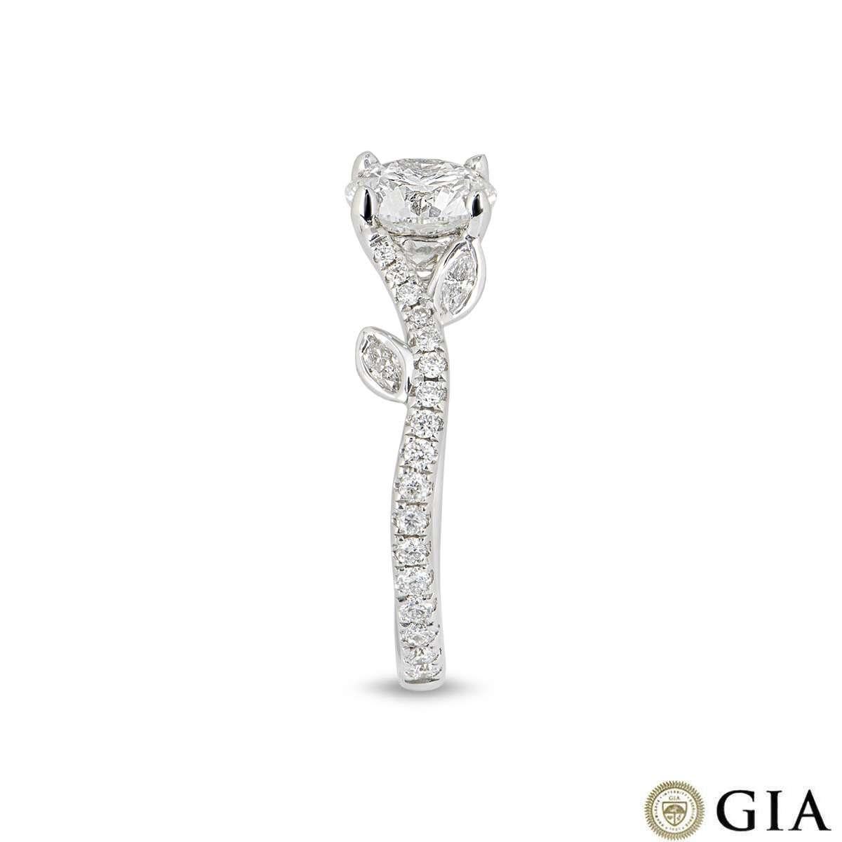 A gorgeous 18k white gold diamond engagement ring. The ring features an intricate floral design set to the centre with a round brilliant cut diamond weighing 1.01ct, E colour and VVS1 clarity. The centre stone is enhanced by the graceful pave