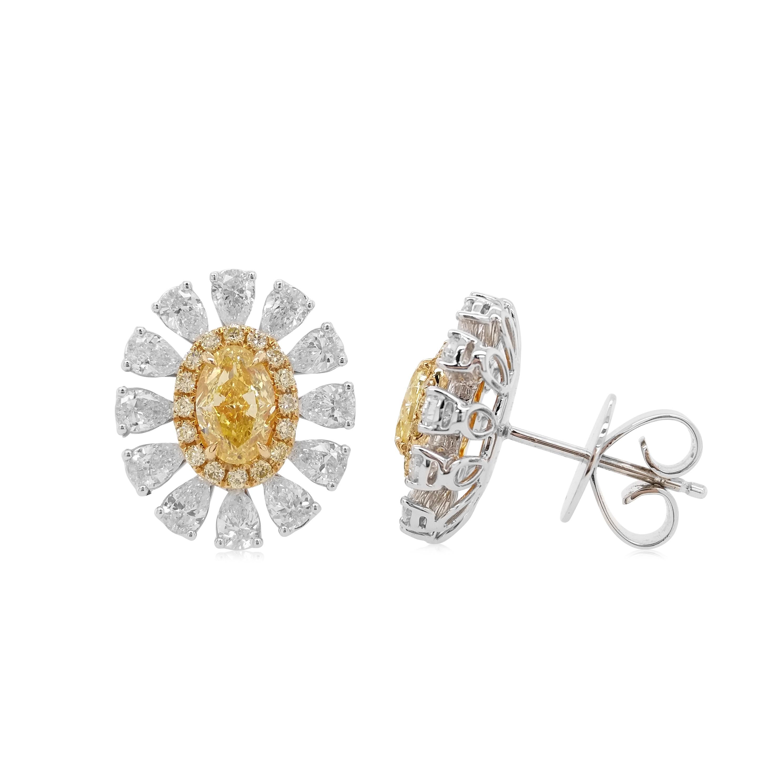 Diese einzigartigen blumenförmigen Ohrringe bestechen durch ihre ovalen gelben Diamanten im Herzen des Designs. Die satte Farbe dieser Diamanten wird durch das zarte Blumenmuster aus 18 Karat Weißgold, das durch eine Kombination birnenförmiger