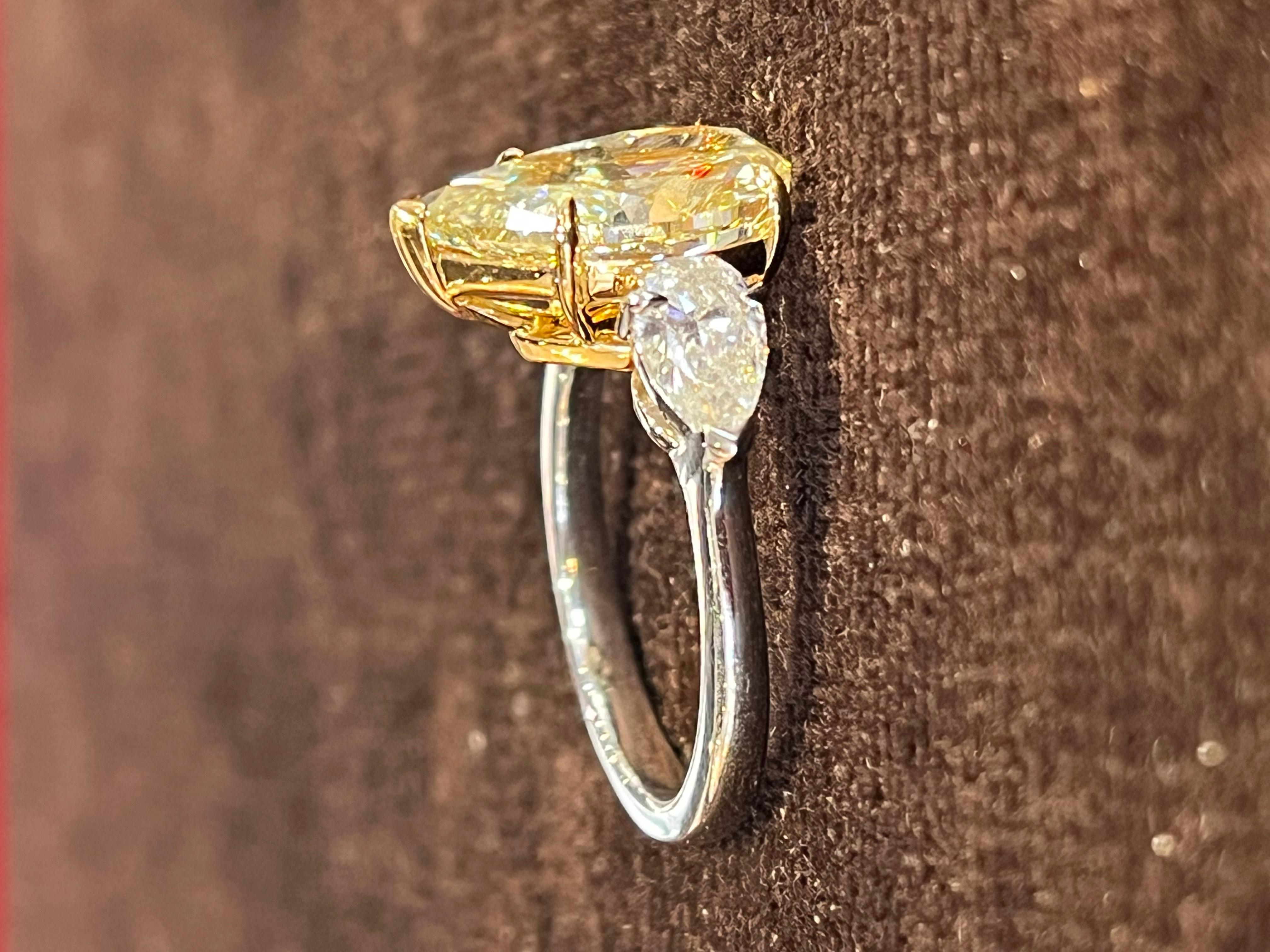 Stones: Yellow Diamond
             Diamonds

Shape: Pear Modified Brilliant 

Carat Weight: Main stone: 4.01cts
                       Side stones: 2 x 0.85cts

Color: Main stone: Z
           Side stones: F

Clarity: Main stone: SI1
           