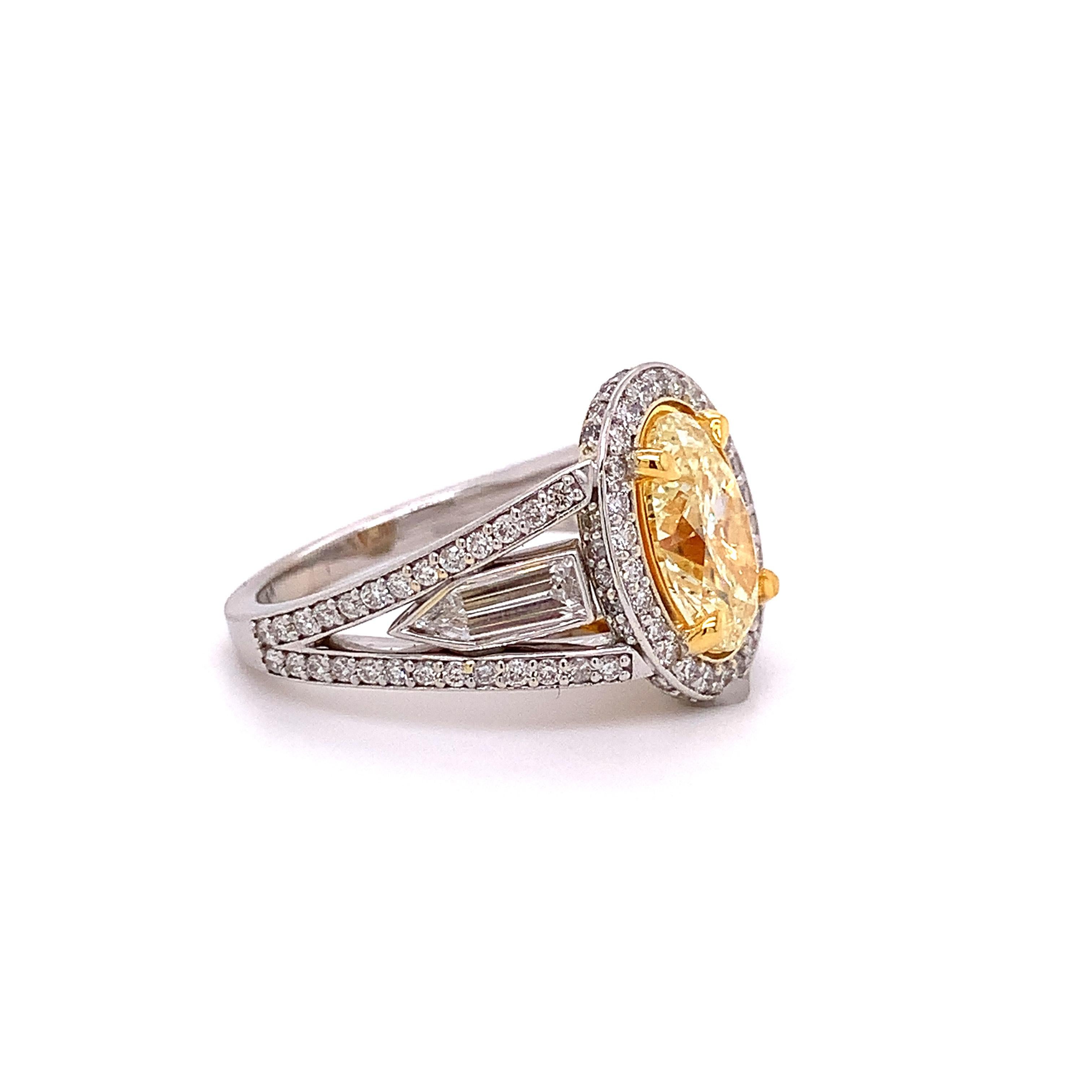 A lovely exceptional engagement ring featuring a yellow (Y-Z color, VS1 clarity) oval-shaped diamond weighing 2.01 carats. 

This ring also features two bullet shaped diamonds (0.49 CTTW) and is set beautifully with white diamonds on the halo and
