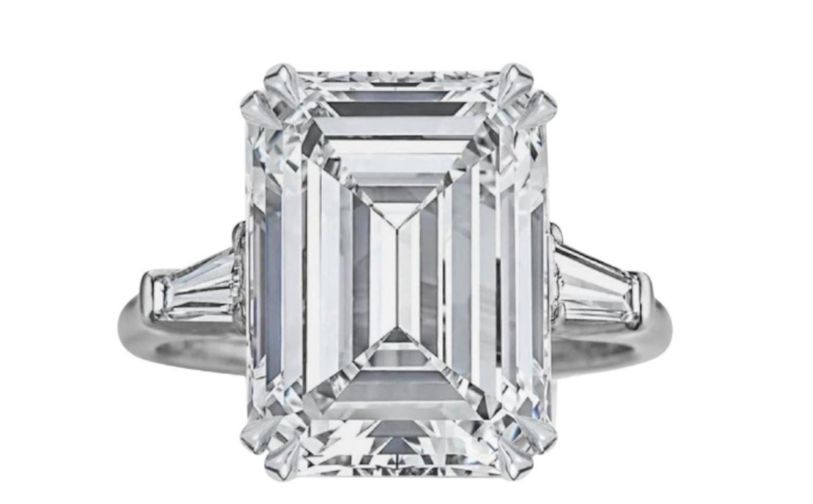 This magnificent three-stone ring showcases a 6.05 carat emerald-cut diamond as its centerpiece, offering timeless elegance and striking brilliance. Set in platinum, the ring combines luxury with enduring strength.

Certified by GIA, the diamond is