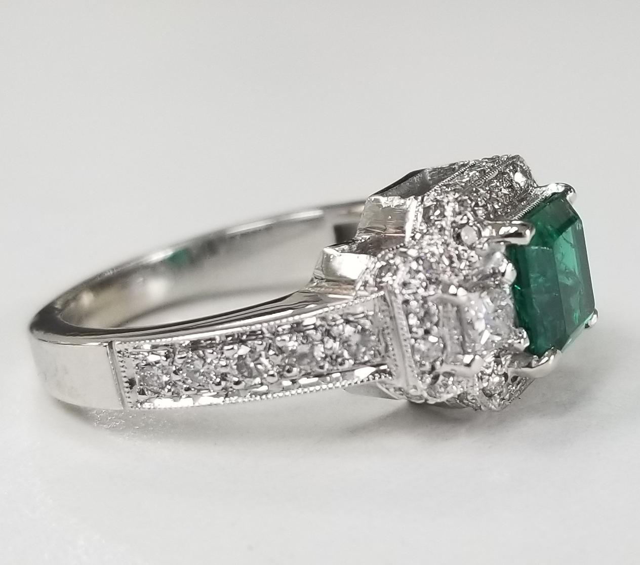 14 karat white gold square emerald and halo diamond ring, containing 1 GIA square emerald of gem quality weighing 1.26cts., flanked with 2 princess cut diamonds on either side of fine quality weighing .40pts. and 40 round full cut diamonds of fine