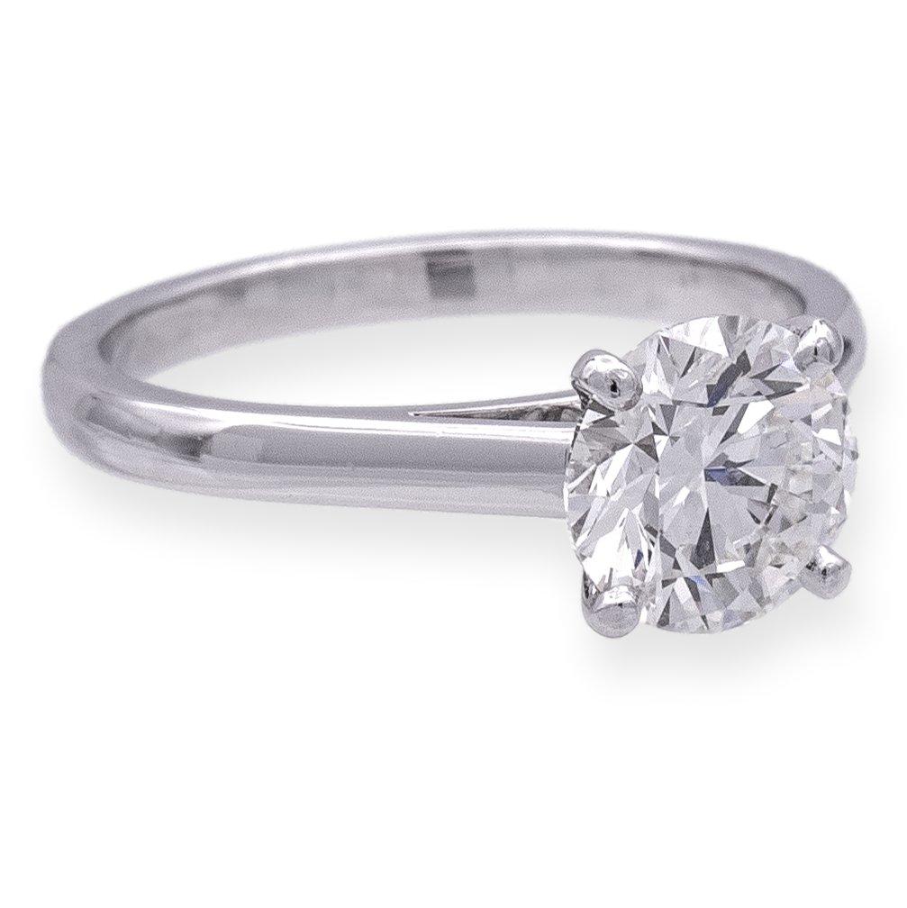 DeBeers engagement ring finely crafted in platinum featuring a round brilliant cut diamond center weighing 1.29 carats, H color and SI1 clarity set in a four prong 