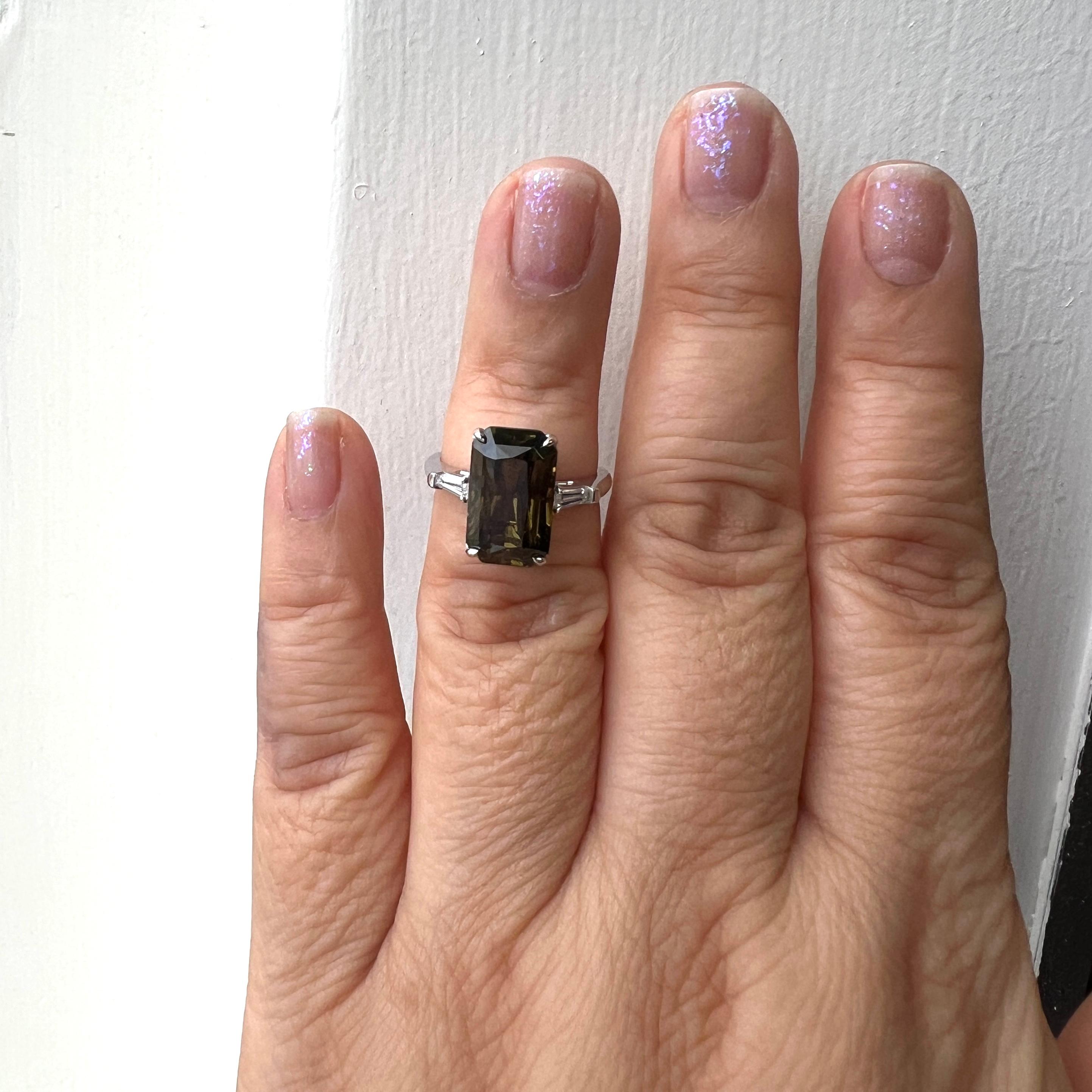 Splendida alessandrite di 8,03 ct. con baguette di diamanti bianchi e luminosi di buona qualità.  L'alessandrite passa dal verde marroncino al giallo marrone. 
Realizzato a mano in platino.  Anello misura 6,5.  Viene fornito con certificato GIA.