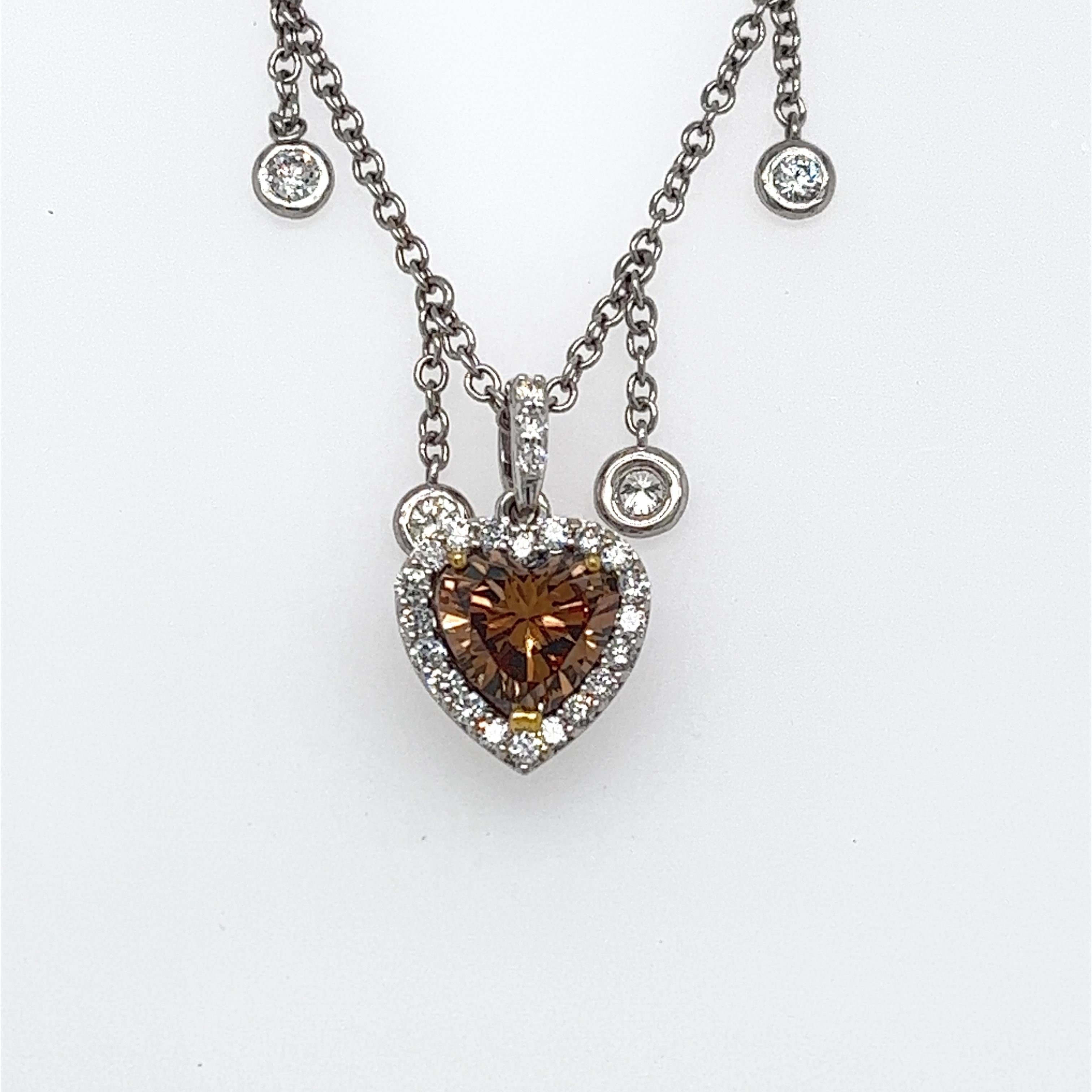 Offered here is a classic heart shape diamond framed with round diamonds dangling on a diamond by the yard chain, all in 18kt gold.
Center Diamond: 1.31 carats, G.I.A certified Fancy Dark Yellowish Brown, Even and VS1 in clarity. ( 7.46mm by 7.69mm