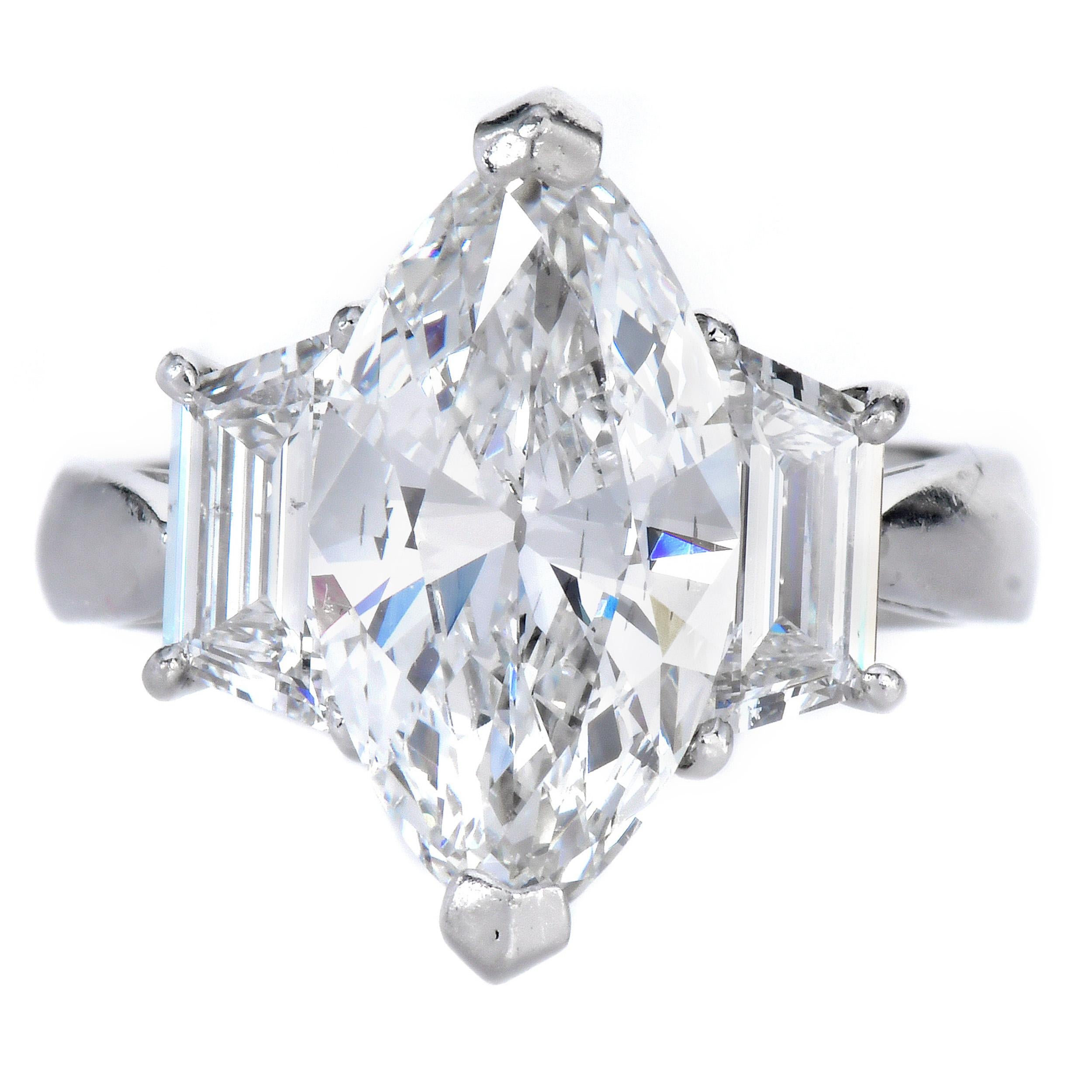 Un impresionante anillo de compromiso de platino que exhibe un diamante marquesa de 3,01 quilates, certificado por el GIA, de color F y claridad VS2. La piedra central, bellamente alargada, está acentuada por diamantes de talla trapezoidal que suman