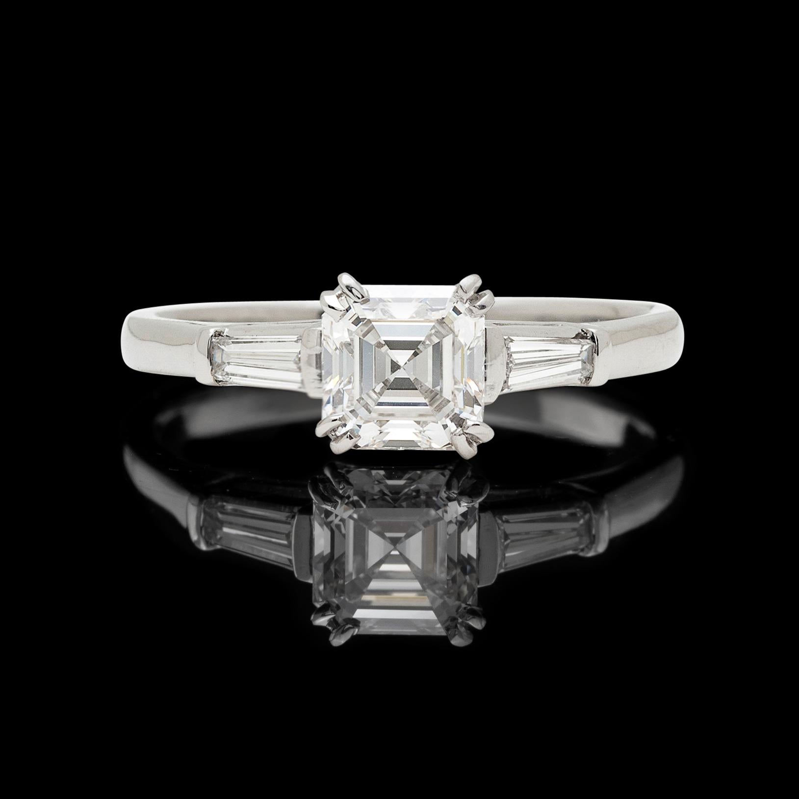 Much-desired, the Asscher-cut is a connoisseur's diamond. This beautiful example weighs 0.88 carat, and is a GIA F color, VS2 clarity. Flanked by two tapered baguette-cut diamonds, the ring totals 1.20 carats. The platinum ring weighs 3.7 grams, and