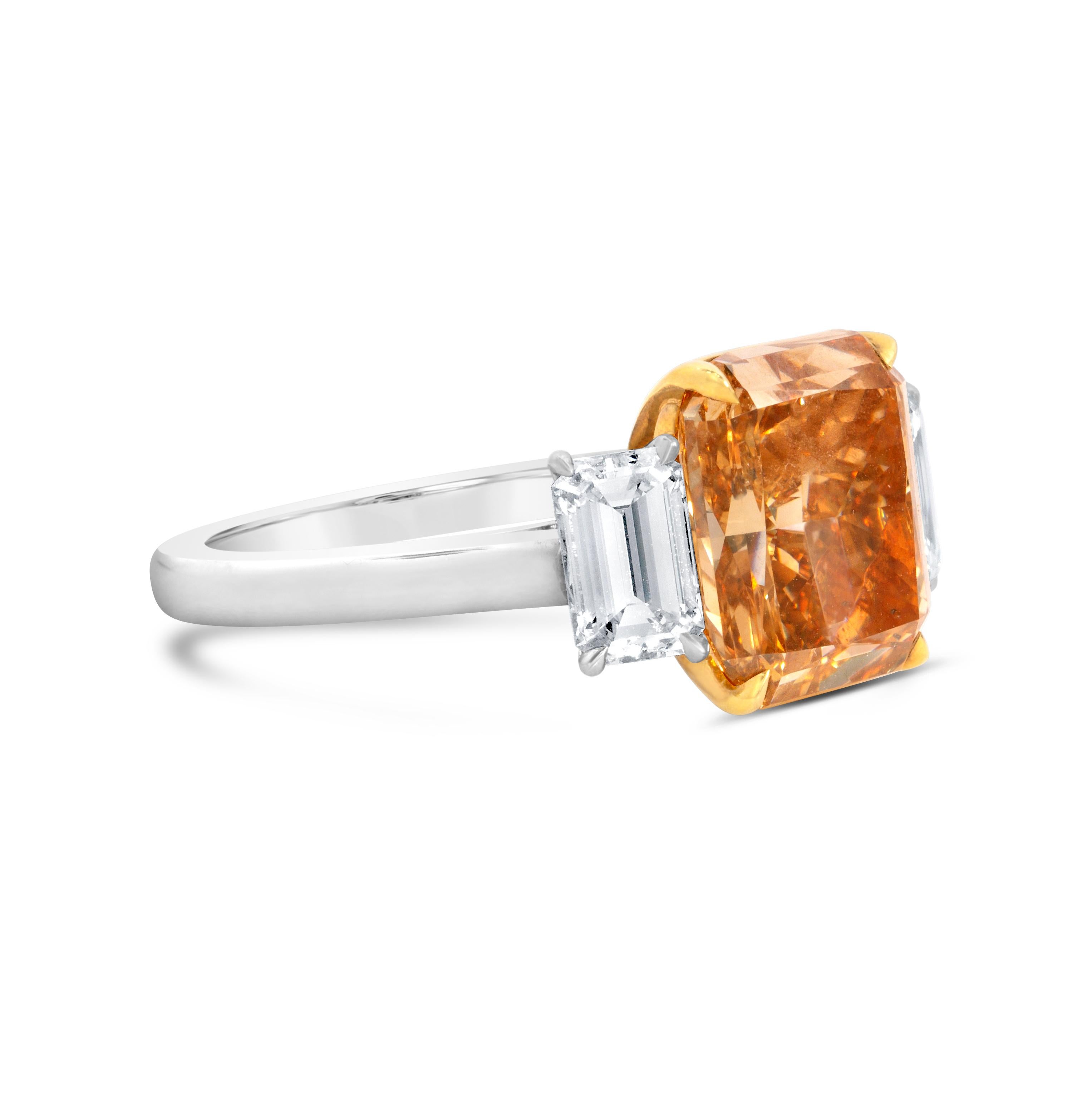 A gorgeous engagement ring, showcasing a 4.00 carats radiant cut Fancy Deep Brownish-Yellowish Orange diamond, set on a classic four prong 18K yellow gold basket. Flanked by emerald cut diamonds weighing 1.01 carats total. Finely made with a