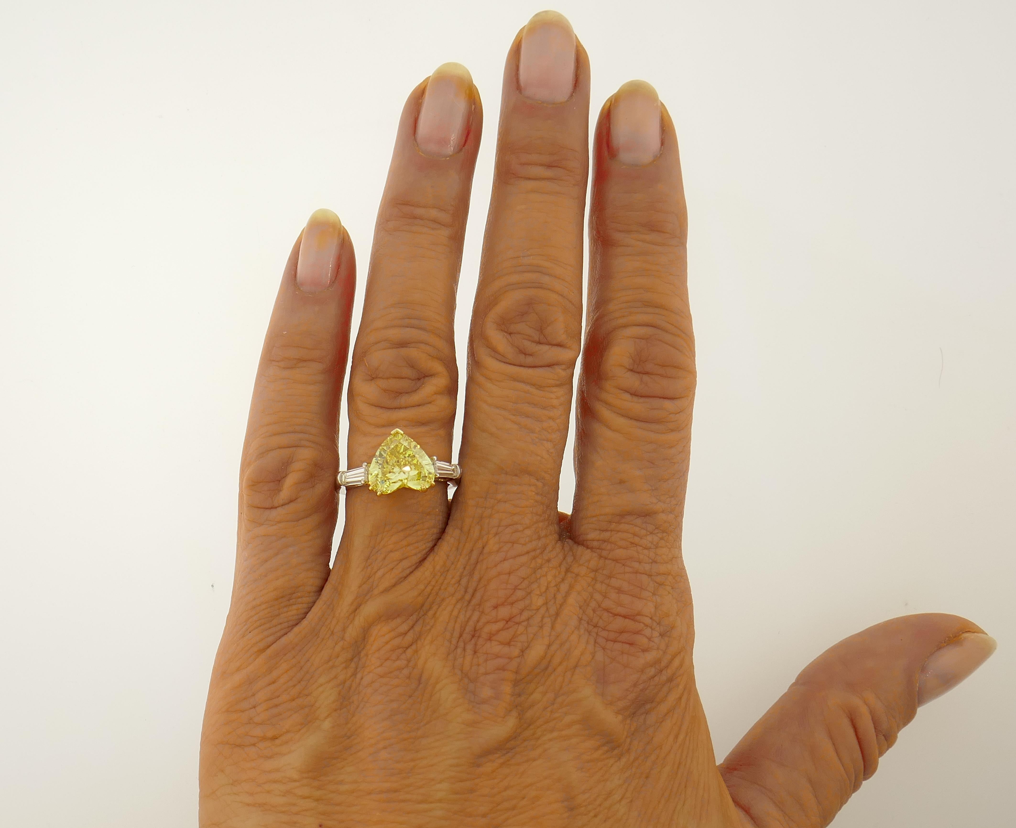Magnificent heart-shape yellow diamond solitaire ring! Features a 2.64-carat natural fancy vivid yellow heart brilliant cut diamond flanked by two tapered baguette cut white diamonds. The fancy yellow diamond comes with a GIA Colored Diamond Grading