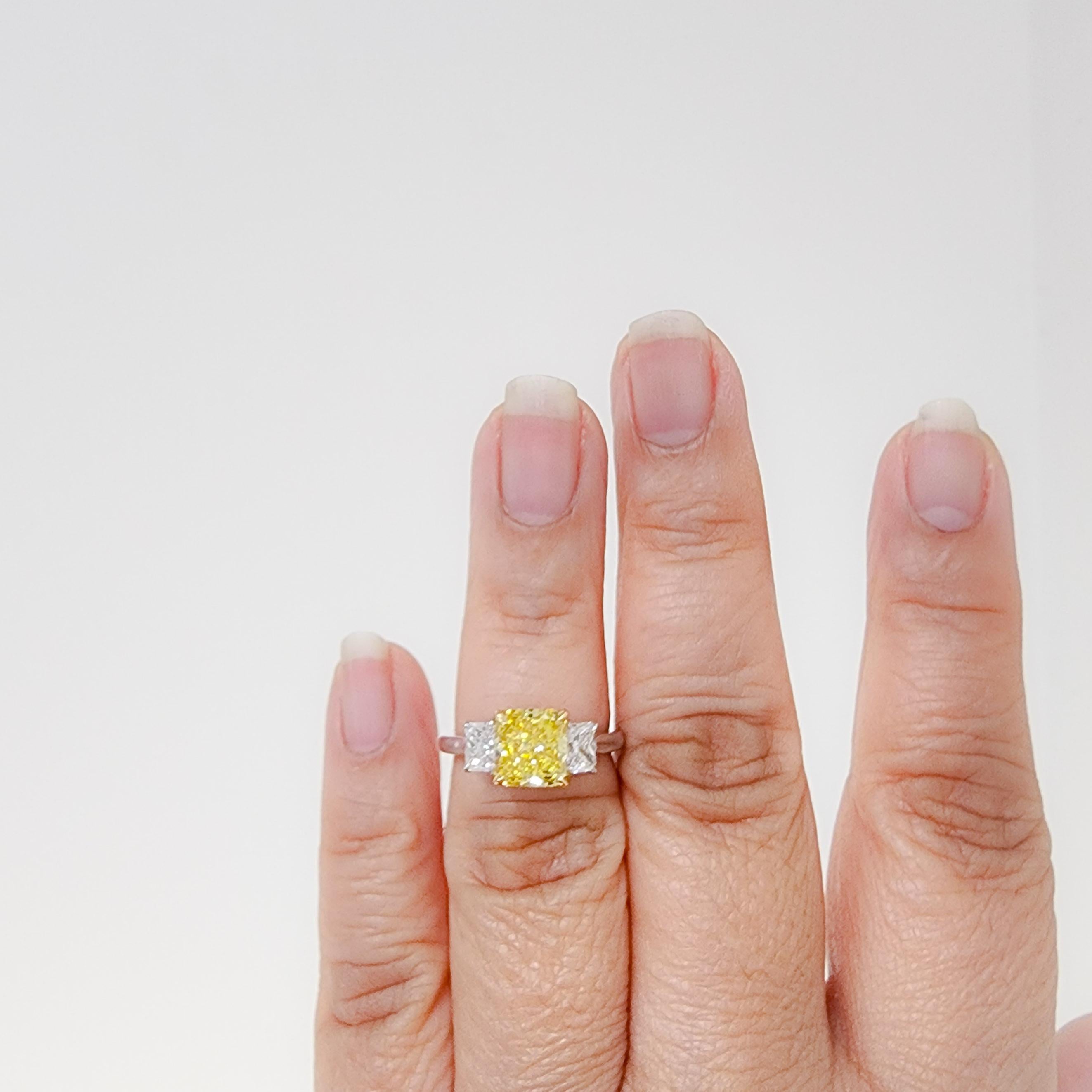 Gorgeous 2.19 ct. fancy vivid yellow diamond radiant, clarity I1 with two good quality white diamond radiants on the sides.  Handmade in 18k yellow gold and platinum.  Ring size 6.5.  GIA certificate included.