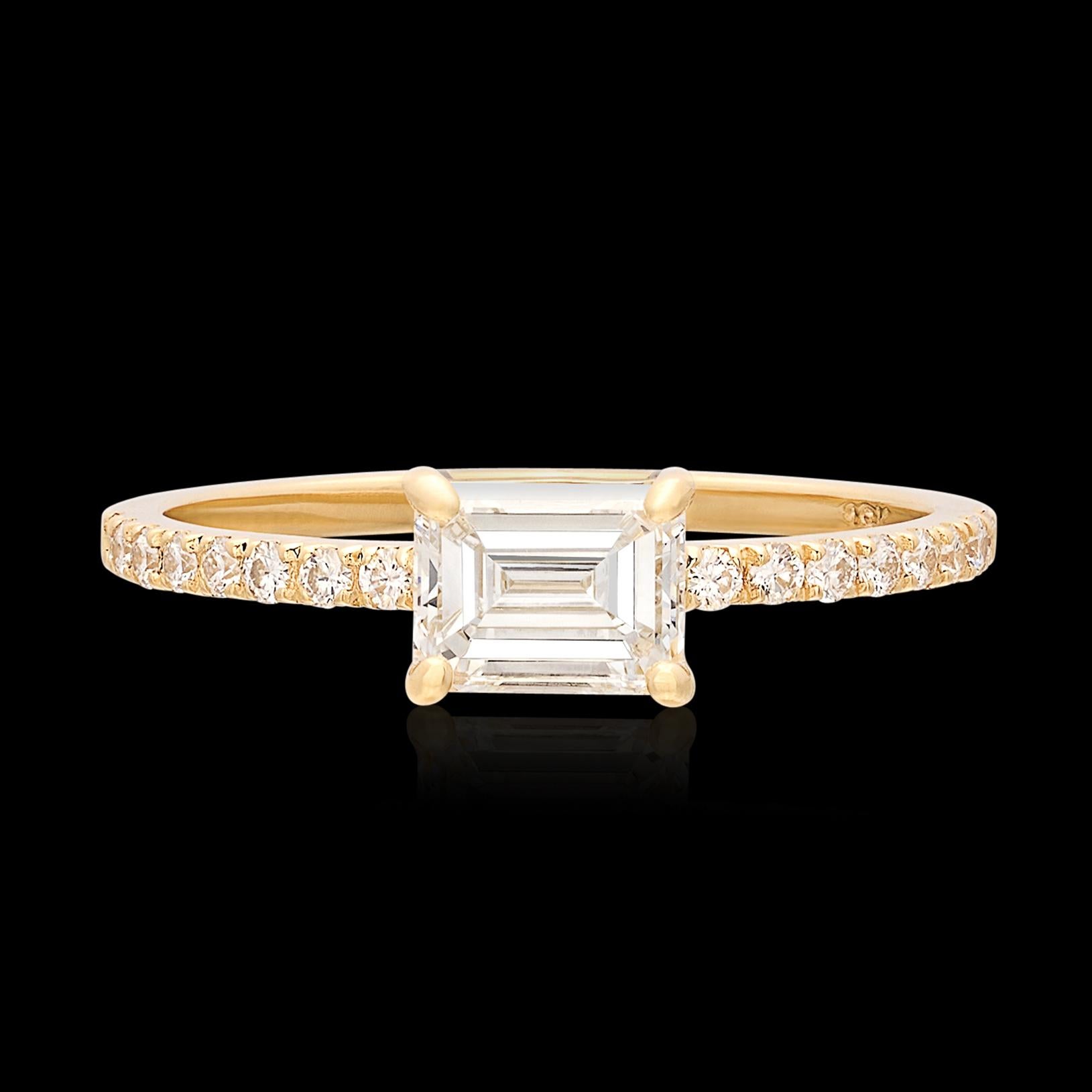 Este anillo brilla mucho más que su tamaño. El anillo de compromiso de oro de 18 quilates lleva un diamante talla esmeralda de 0,69 quilates, graduado en color G y claridad VVS1 por el Instituto Gemológico de América, y engastado horizontalmente en