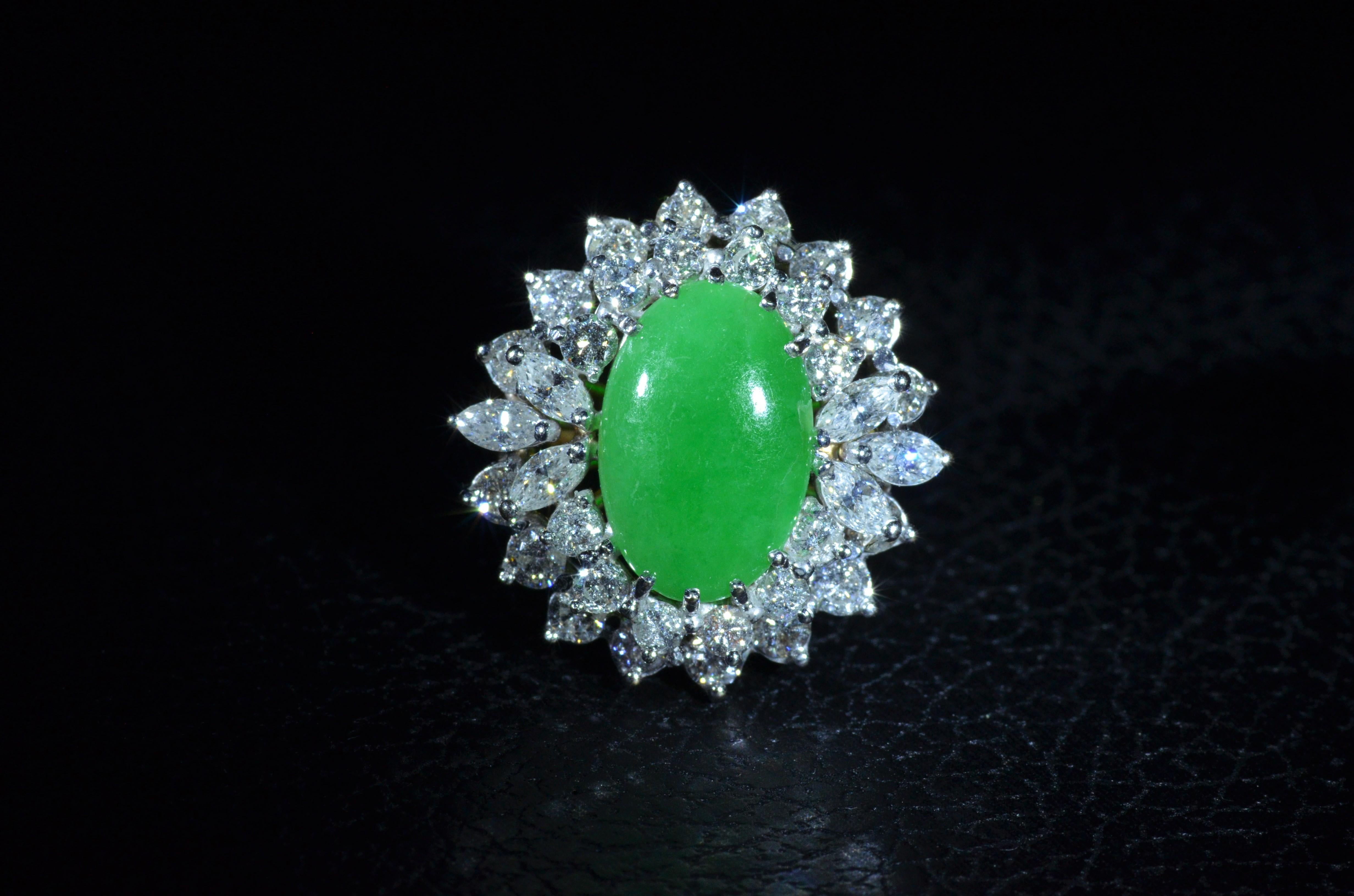 Ladies 18 Karat yellow gold and white gold ring set with a Gemological Institute of America Graded Natural Jadeite Jade.  The jade is oval and cabochon in shape with a medium Green vivid in saturation and translucent by natural. Surrounding the