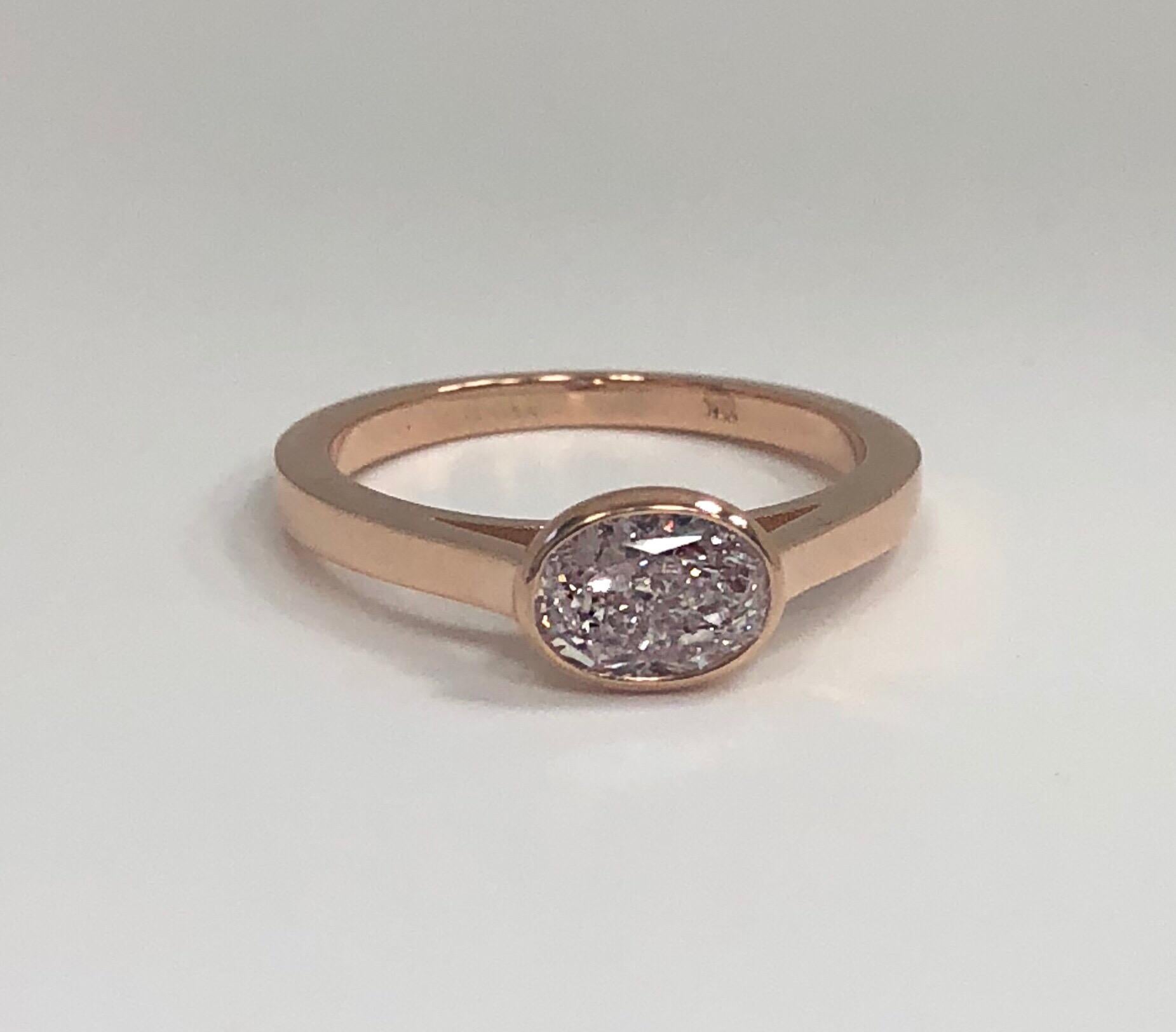 The GIA certified Light Pink diamond ring, by Josef C, is centered on a .94 carat Oval Modified Brilliant Cut diamond, SI2 Clarity, mounted in a cathedral style bezel setting. 