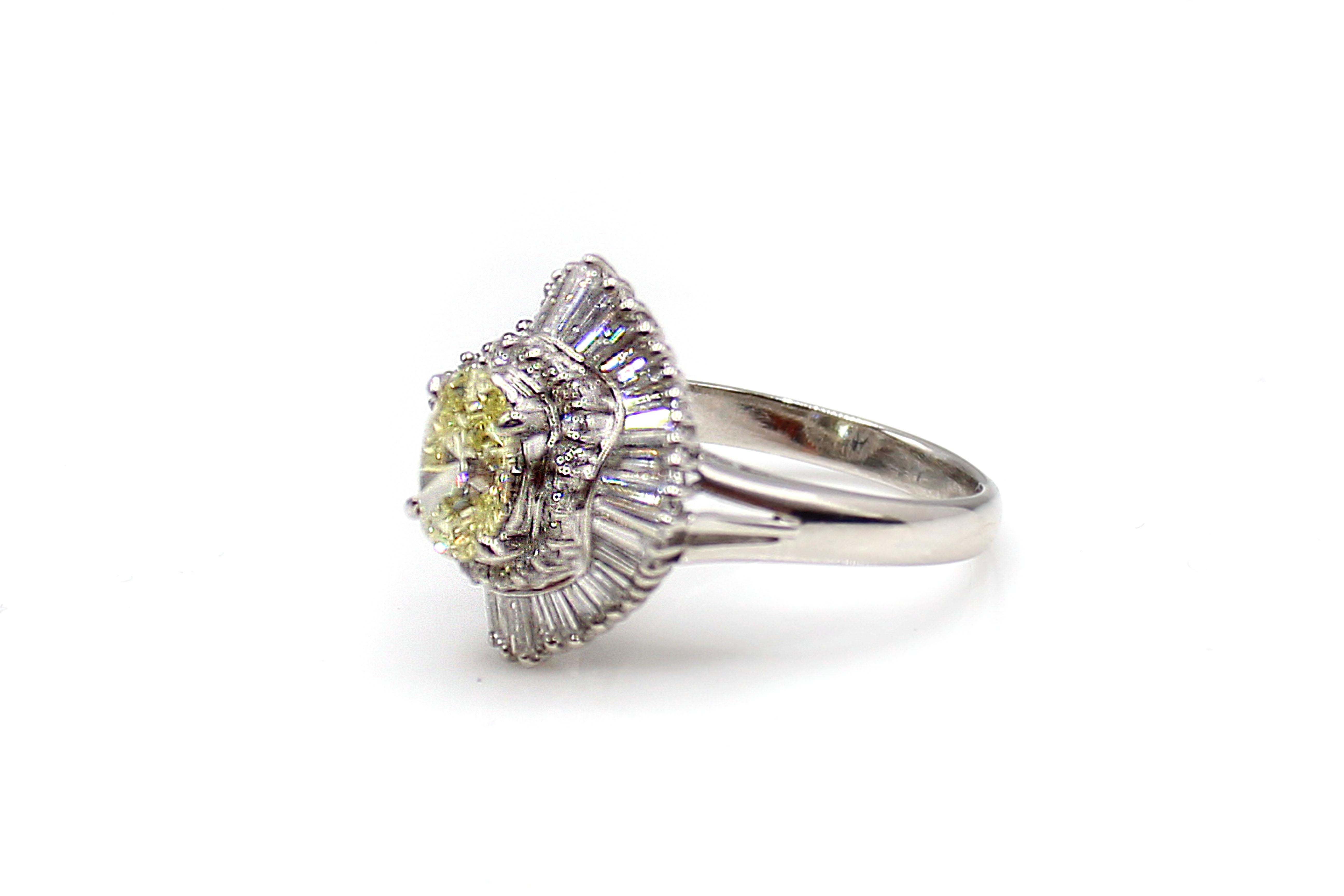 Wonderfully hand-crafted, this 1970s ballerina ring features a beautiful lemon colored natural fancy yellow oval diamond weighing 1.12 carats. The diamond is accompanied by a report from the GIA. Surrounding the center diamond are 20 round brilliant
