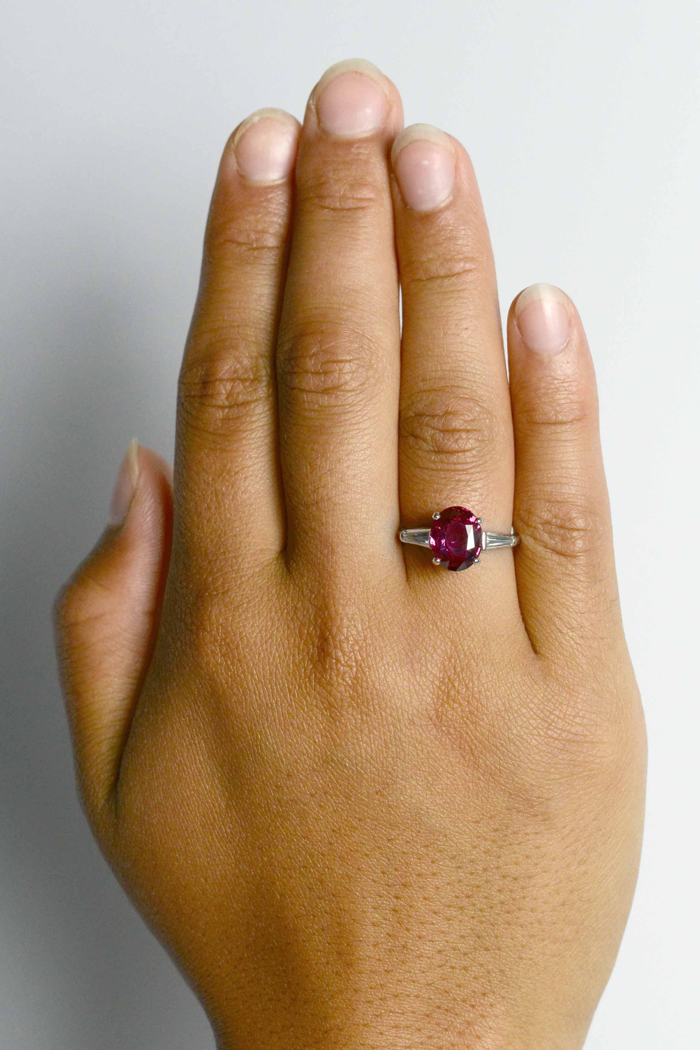 This regal ruby engagement ring boasts a GIA certified 3.95 carat natural ruby of a deeply saturated red. So tantalizing, with a captivating hue and shimmering luster, the oval solitaire complimented by diamond baguette shoulders completed by a