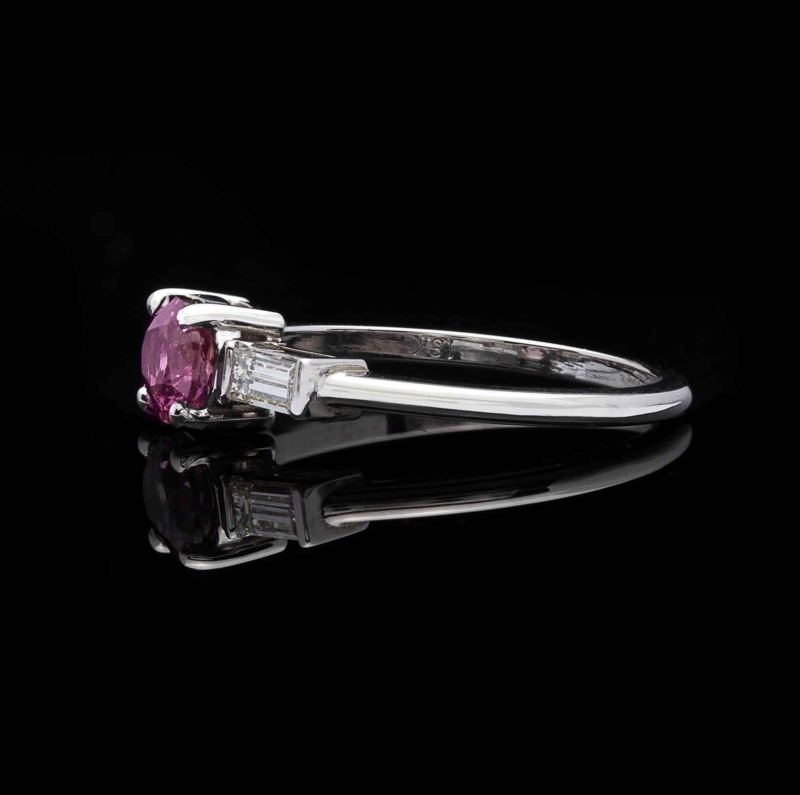 This twist on a classic ring design is perfect for the lover of all things pink! It features a 1.02-carat oval unheated purplish pink sapphire, set east-west in horizontal fashion, and simply accented with two straight baguette-cut diamonds, with a