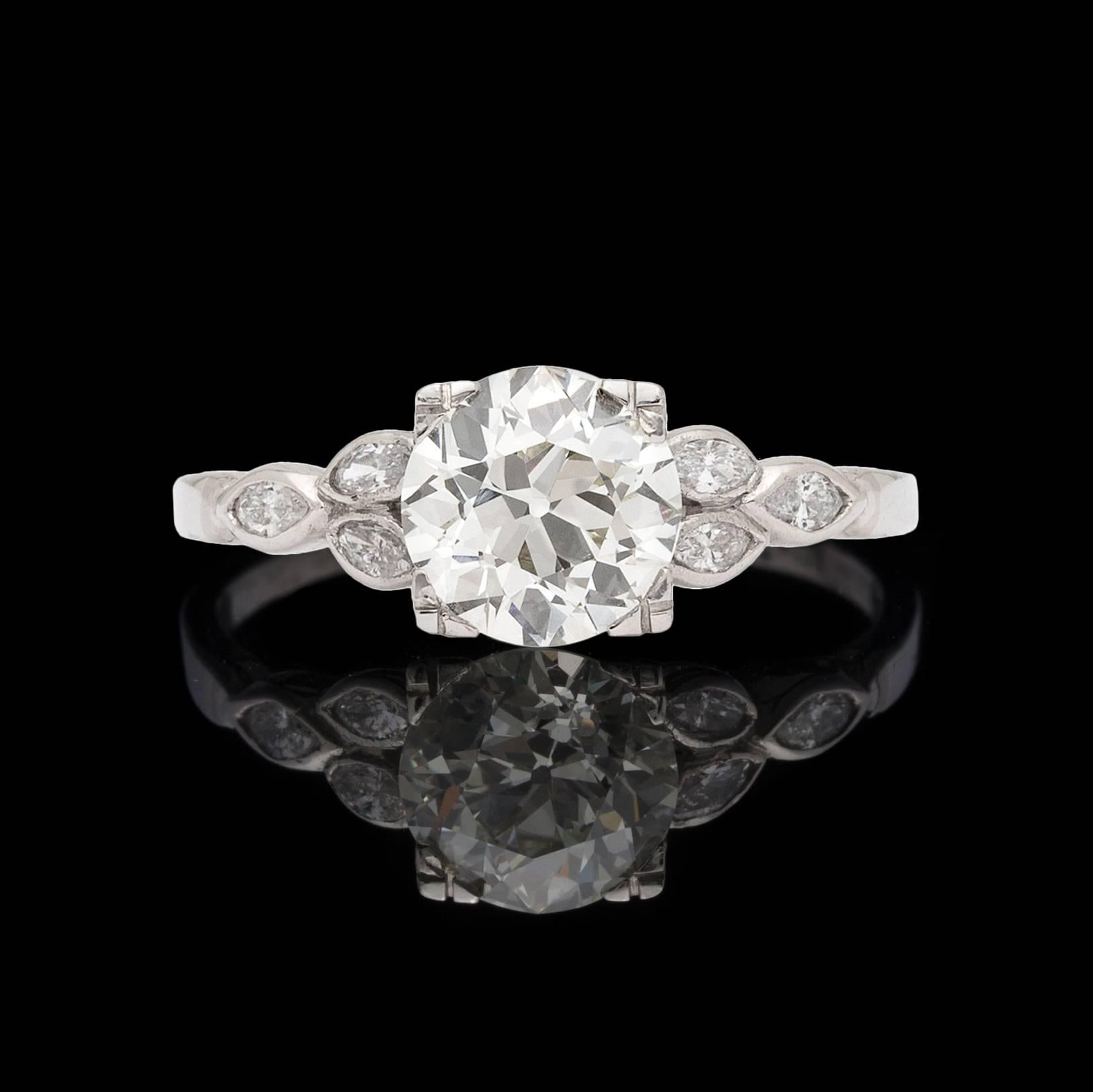 Channeling beauty from the 1930's, this delicate platinum ring features a circular-cut diamond weighing 1.29 carats, graded L/VVS2 by GIA, and accented by 6 bezel-set marquise-cut diamonds. Total diamond weight for the ring is approximately 1.54