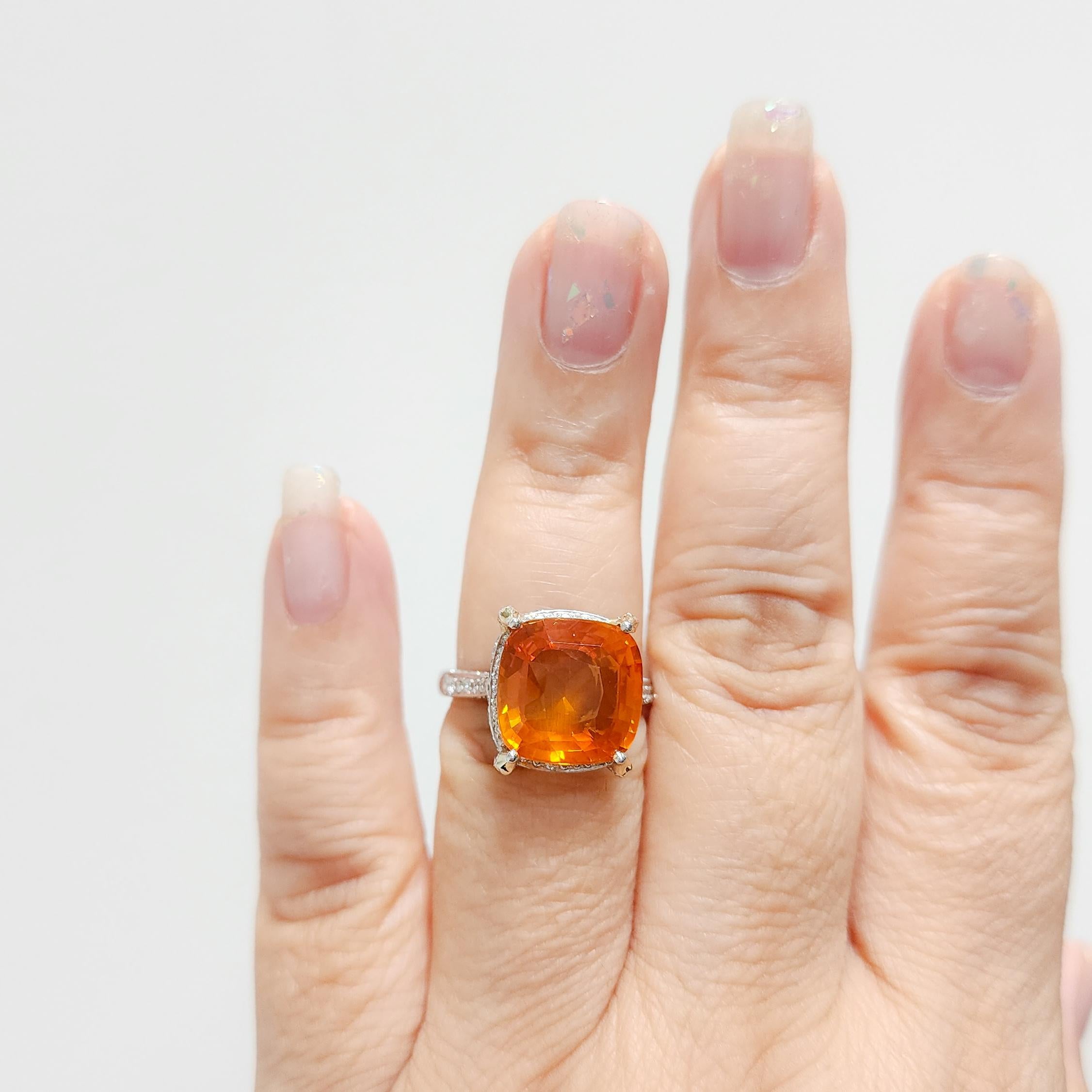 Stunning bright orange 10.29 ct. sapphire cushion with good quality white diamond rounds.  Handmade in platinum.  Ring size 6.75.  GIA certificate included.