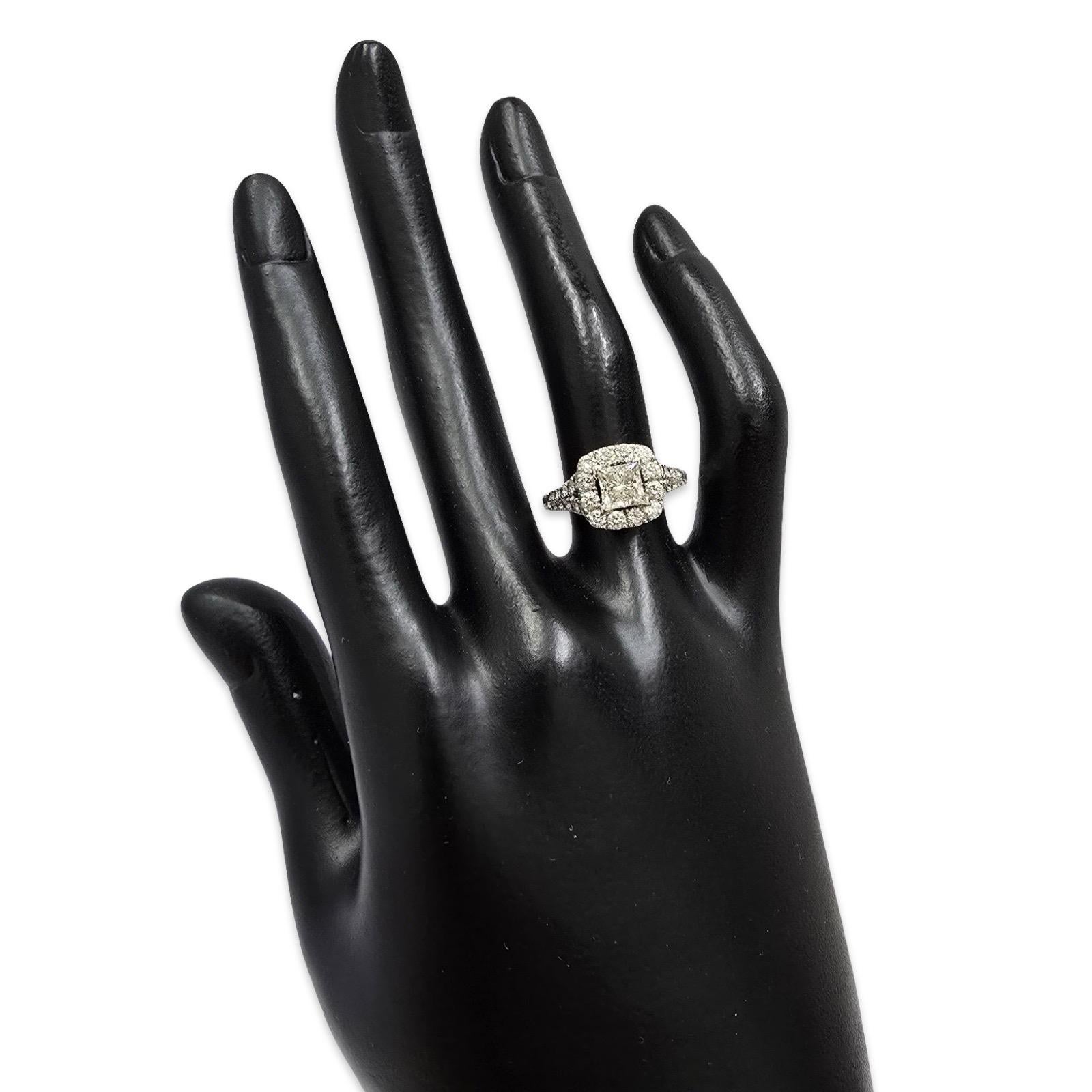 Questo raffinato anello di fidanzamento a forma di aureola è incentrato su un diamante con taglio princess J/VS1 certificato GIA da 0,90 carati che si distingue per la sua geometria nitida, il suo fuoco brillante e la sua limpidezza. La moderna