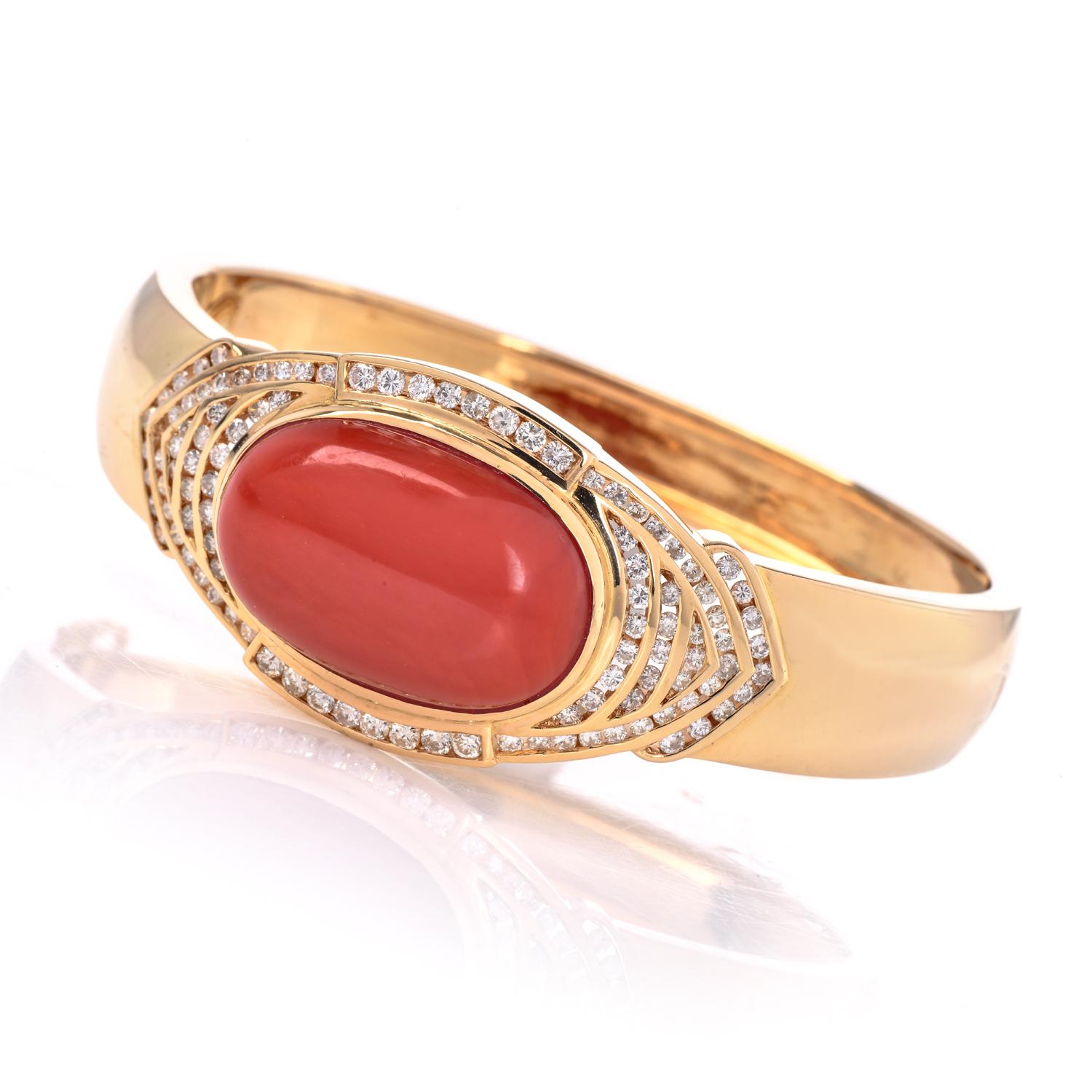 Bracelet manchette en or jaune 18 carats avec corail rouge naturel certifié par le GIA et diamants. Le corail est un double cabochon ovale de couleur rouge-orange semi-translucide, sans indication de teinture, serti au centre.

Les diamants sont des