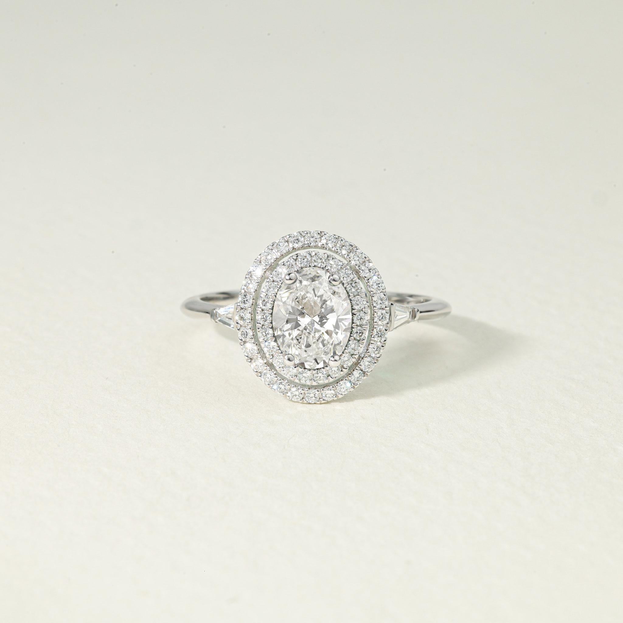 Elevate your love story with this spectacular 1.5ct natural oval-cut diamond engagement ring, a piece that masterfully blends timeless romance with high jewelry craftsmanship. Handcrafted in polished 18K white gold, this exquisite design captures