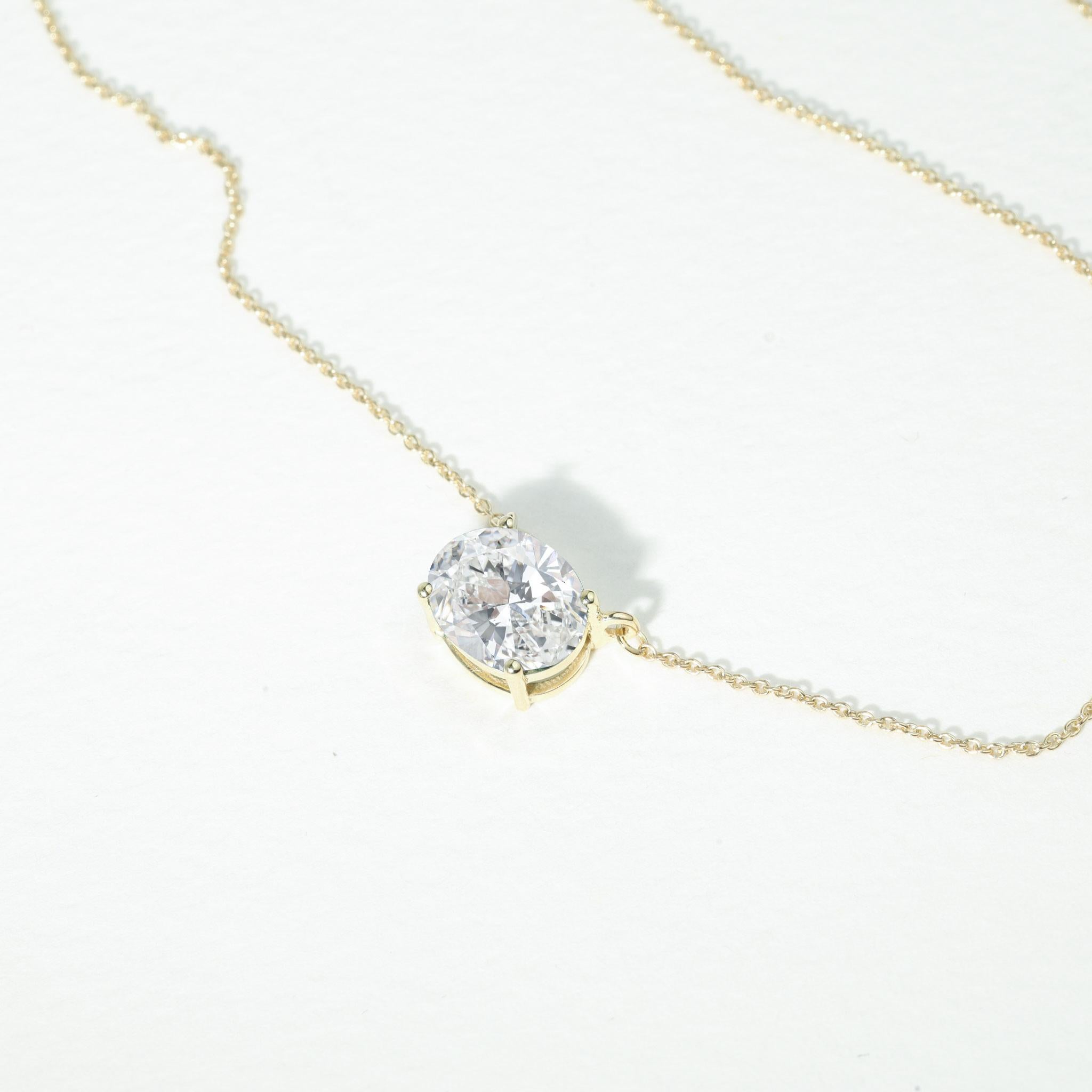 A masterpiece of understated grandeur, this 2ct natural oval-cut diamond solitaire pendant captures the essence of timeless beauty and modern elegance. Nestled in a sleek 18K yellow gold prong setting, the elongated oval silhouette evokes both