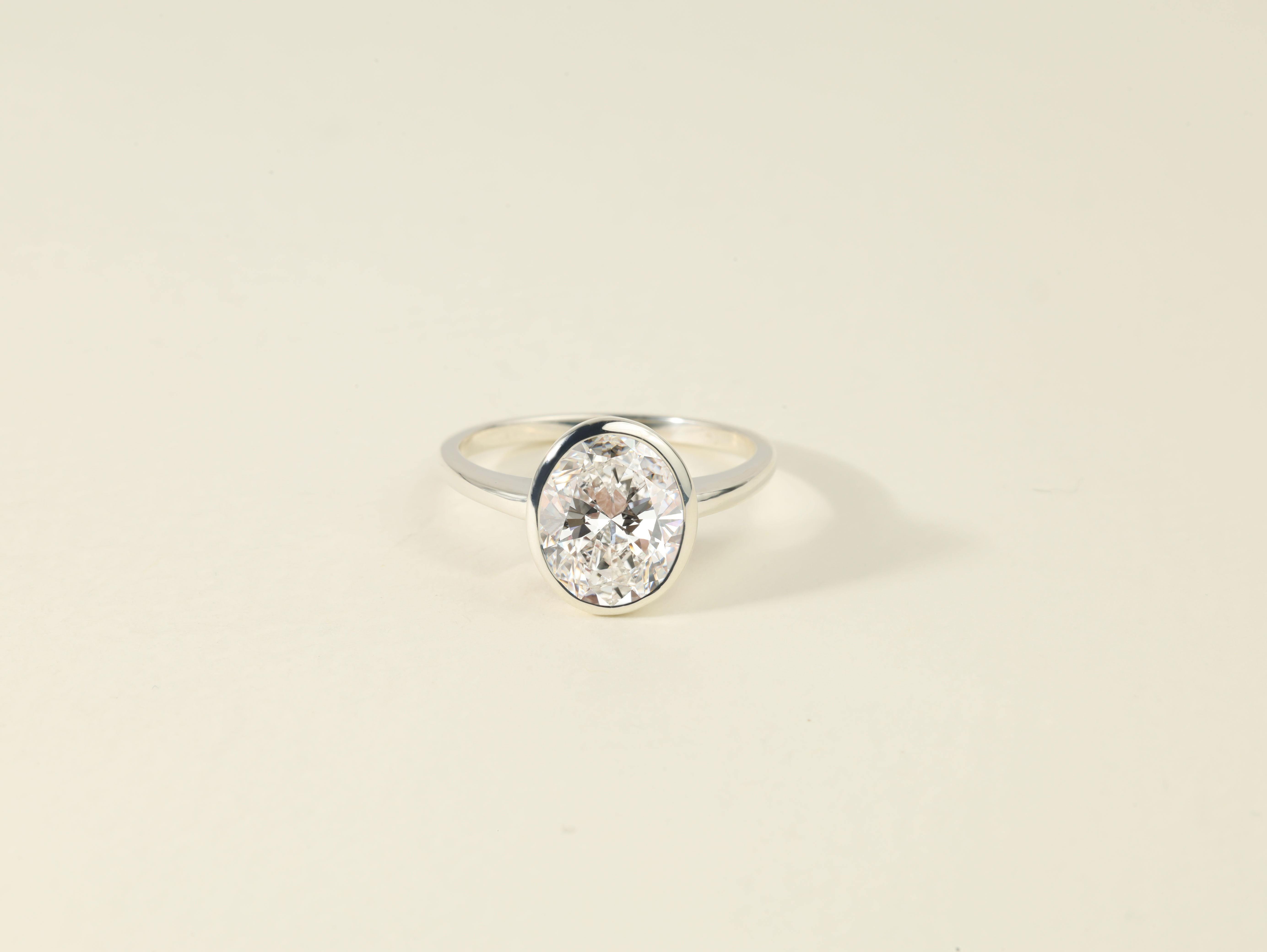A masterpiece of pure elegance and refined luxury, The Signature Oval ring features a breathtaking 3.5ct natural oval-cut diamond, nestled in a sleek bezel setting that amplifies its brilliance while offering a seamless, modern silhouette. Graded VS