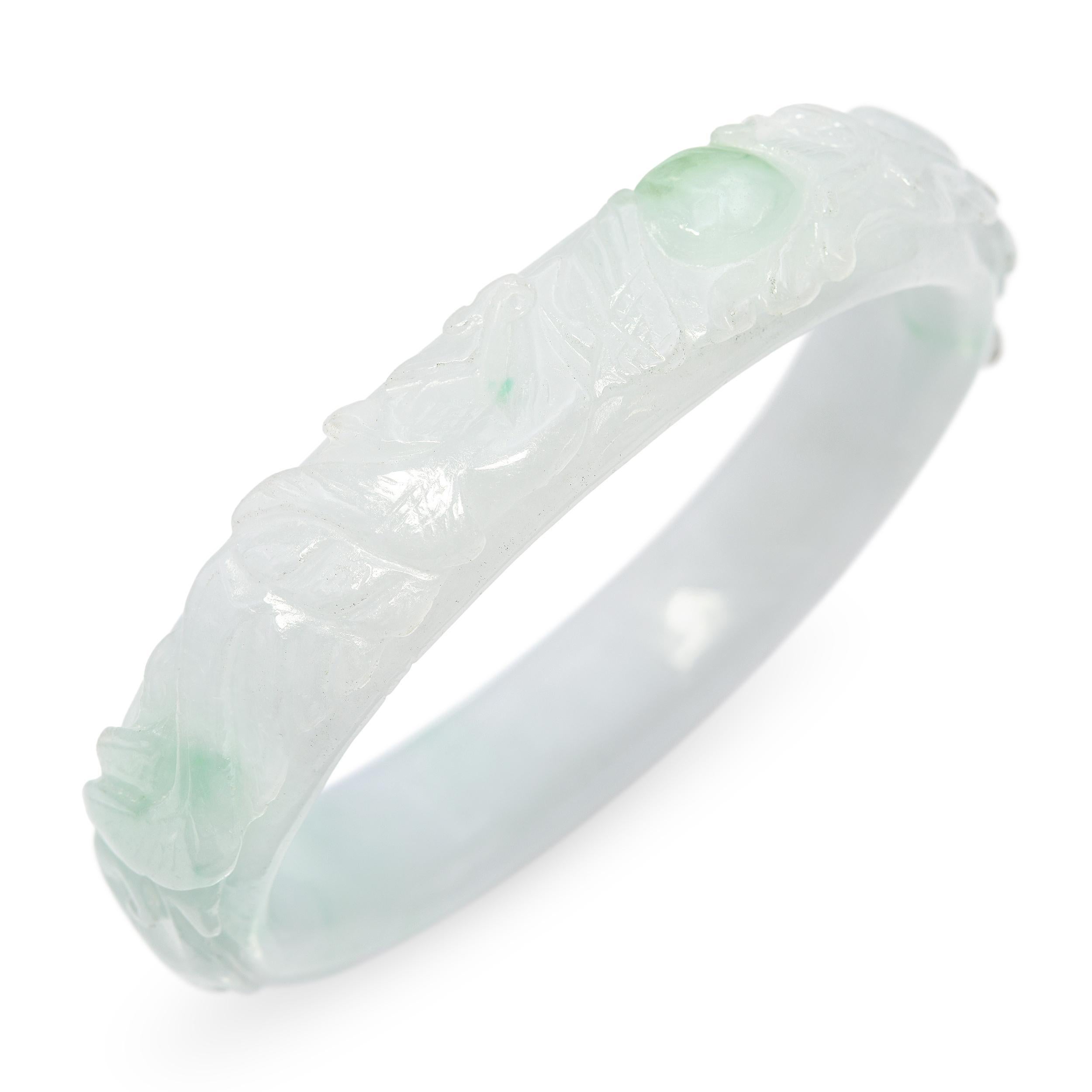 This exquisite GIA-certified jadeite bangle showcases a beautifully carved design in softly variegated tones of light gray and pale green. The stone’s gentle translucency allows light to flow through its surface, revealing subtle natural variations
