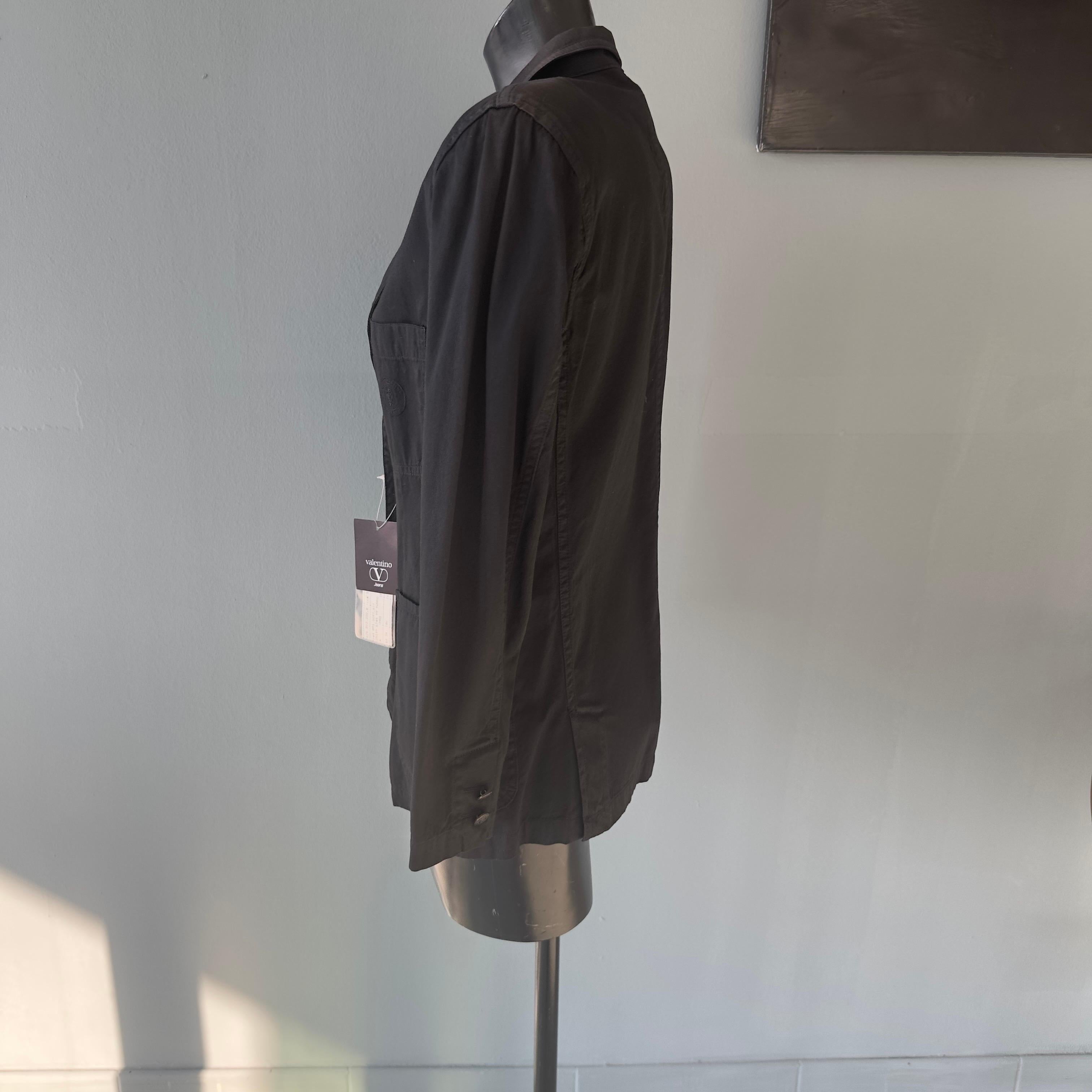 Giacca nera in cotone Valentino jeans anni 80 nuova con cartellino.
Bottoni logati, spacchetti sul retro, spalla imbottita.
due tasche frontali ed una sul petto con logo ricamato tono su tono
Misure:
Spalle 42 cm
Manica 57cm
Petto 47cm
Lunghezza 68cm