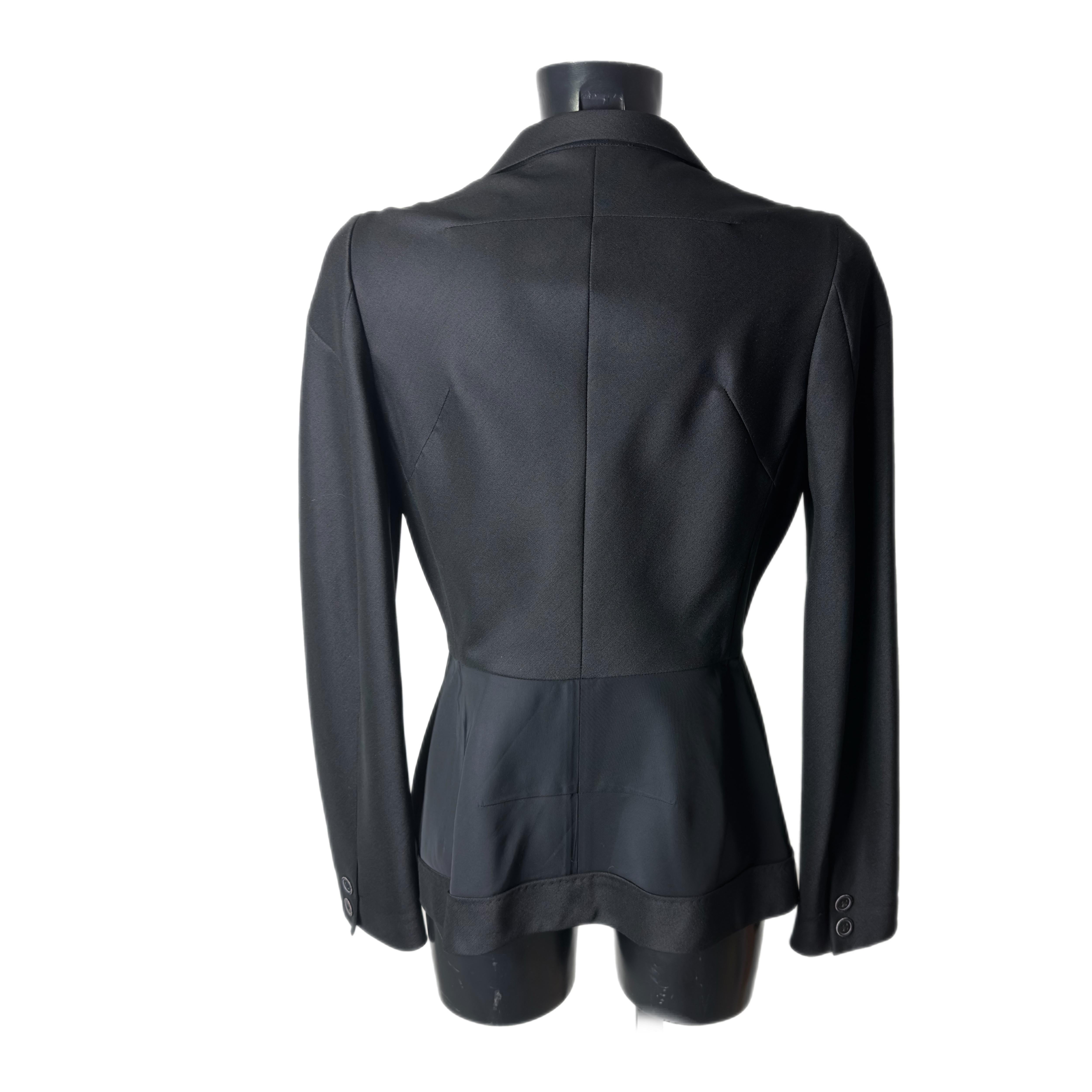 Chic e tradizionale è ciò che rappresenta questo blazer nero di Yohji Yamamoto dalle linee eleganti e lo stile che lo contraddistingue. La sua linea pulita viene segnata in vita con una chiusura a bottone. 
Due tessuti creano un gioco di colore sui