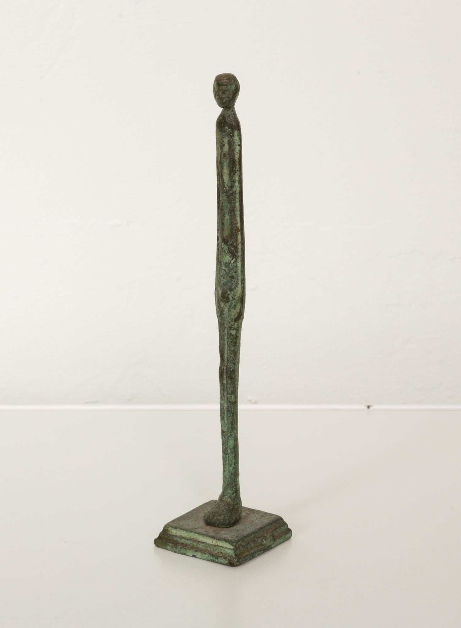 Patinated cast bronze figurative sculpture in the style of Alberto Giacometti. The sculpture features a slender elongated form similar to the cast bronze works that Giacommeti was known for creating. The verdigris patina adds a beautiful character