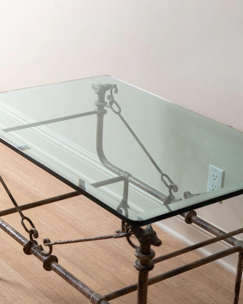 Esta mesa de centro del siglo XX, inspirada en los icónicos diseños de Diego Giacometti y atribuida a Paul Ferrante, es una refinada mezcla de arte y artesanía. La mesa presenta un tablero de cristal biselado que permite ver claramente su intrincada