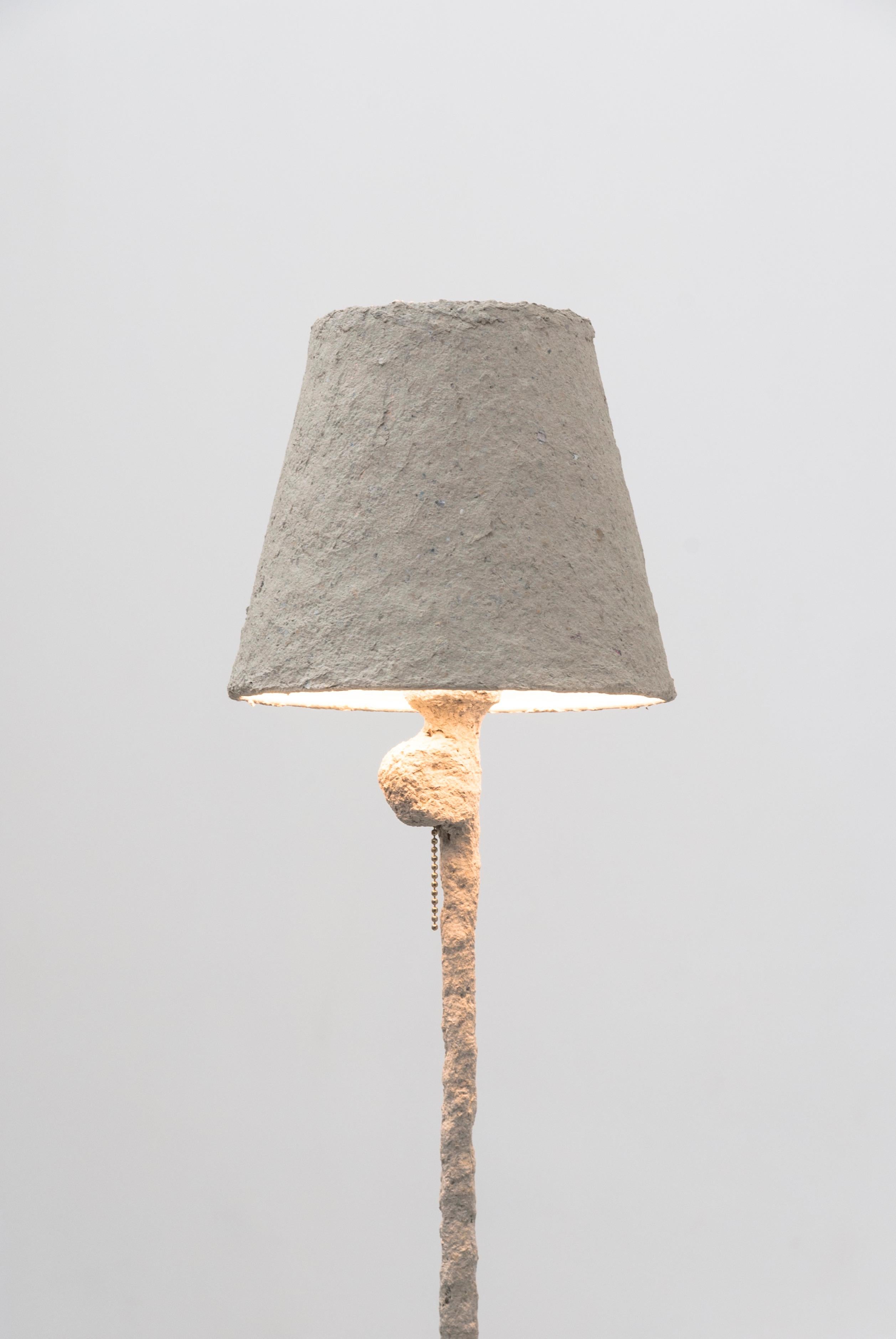 This Giacometti floor lamp by Bailey Fontaine is inspired by the works of Alberto Giacometti. The lamp is sculpted from unconventional materials like paper clay and silicone, which display a rich texture on a biomorphic surface. This minimalistic