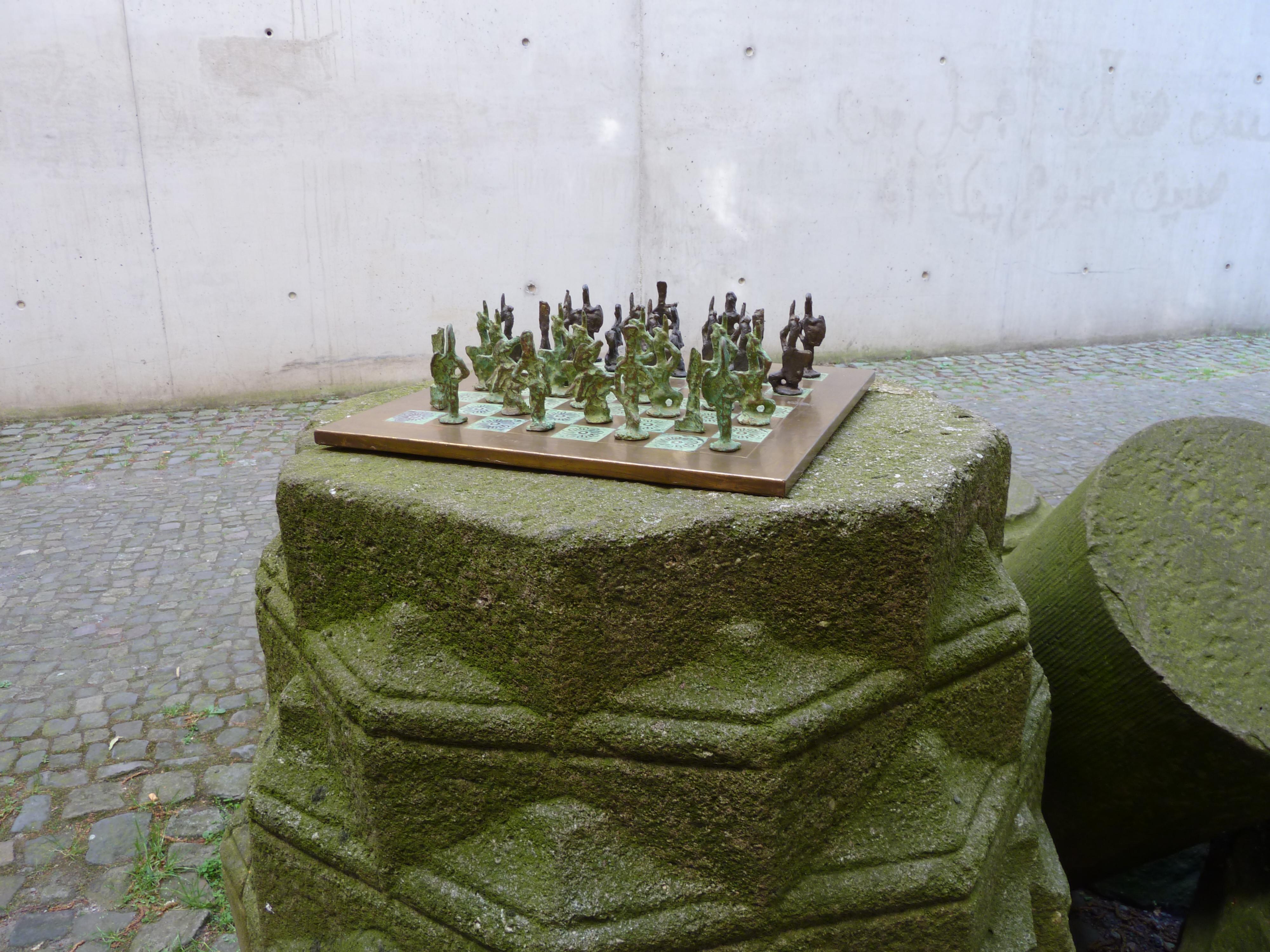 Stunning chess set with cast bronze player pieces and hammered and patinated brass chessboard.