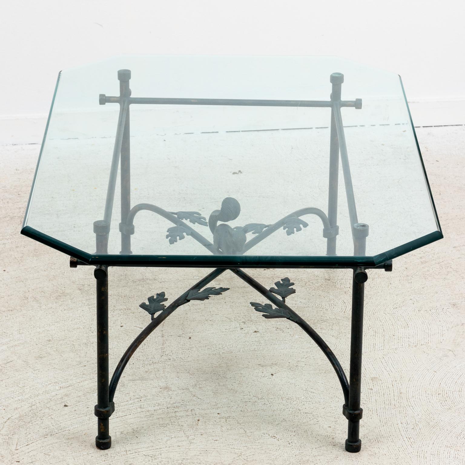 Diego Giacometti inspired cocktail table with detailed squirrel finial base and glass top. The piece also features an x-shaped bottom cross stretcher decorated with metal oak leaves. Please note of wear consistent with age including minor patina and