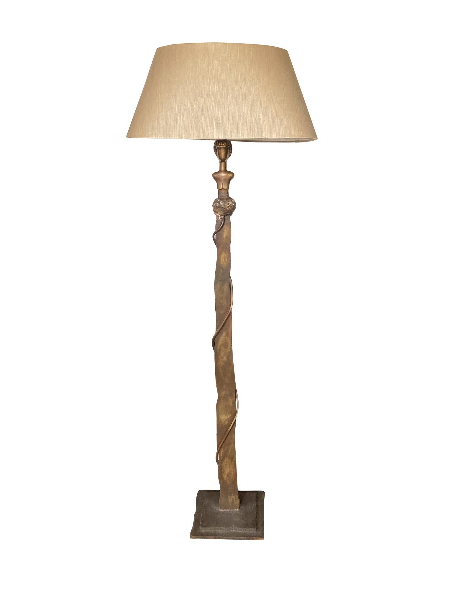 Mid-20th century bronze floor lamp in the style of artist Alberto Giacometti. The lamp stands tall with a flat bar stem on a rectangular base, and culminates at top with a bust of a beautifully abstracted figure. We love the patina of the bronze and