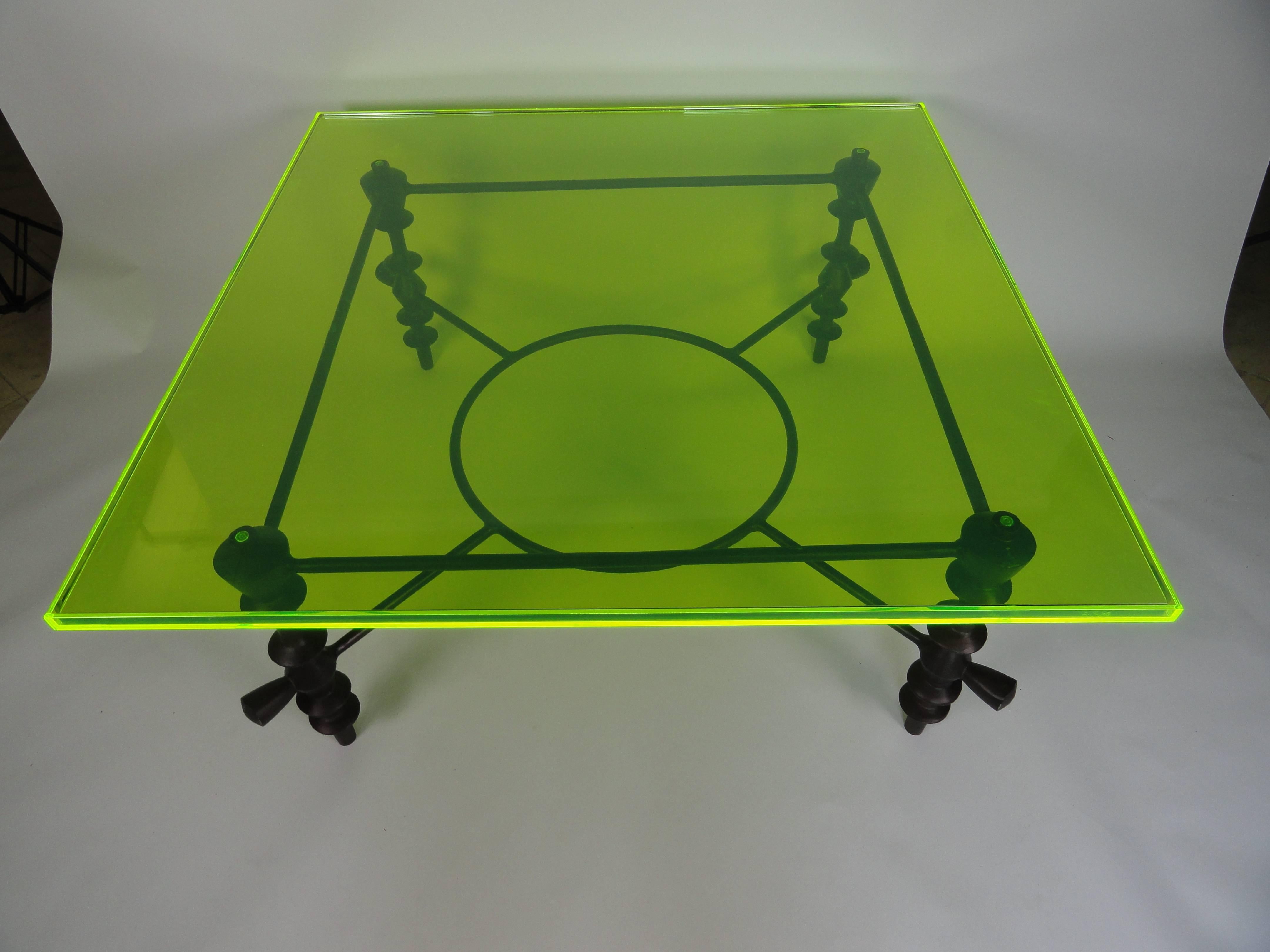Giacometti style coffee table made of metal with a custom green acrylic top. The edges of the top absorb and refract any light which makes them appear to glow bright green. You can see it even with dim light. The acrylic tray top holds a thick piece