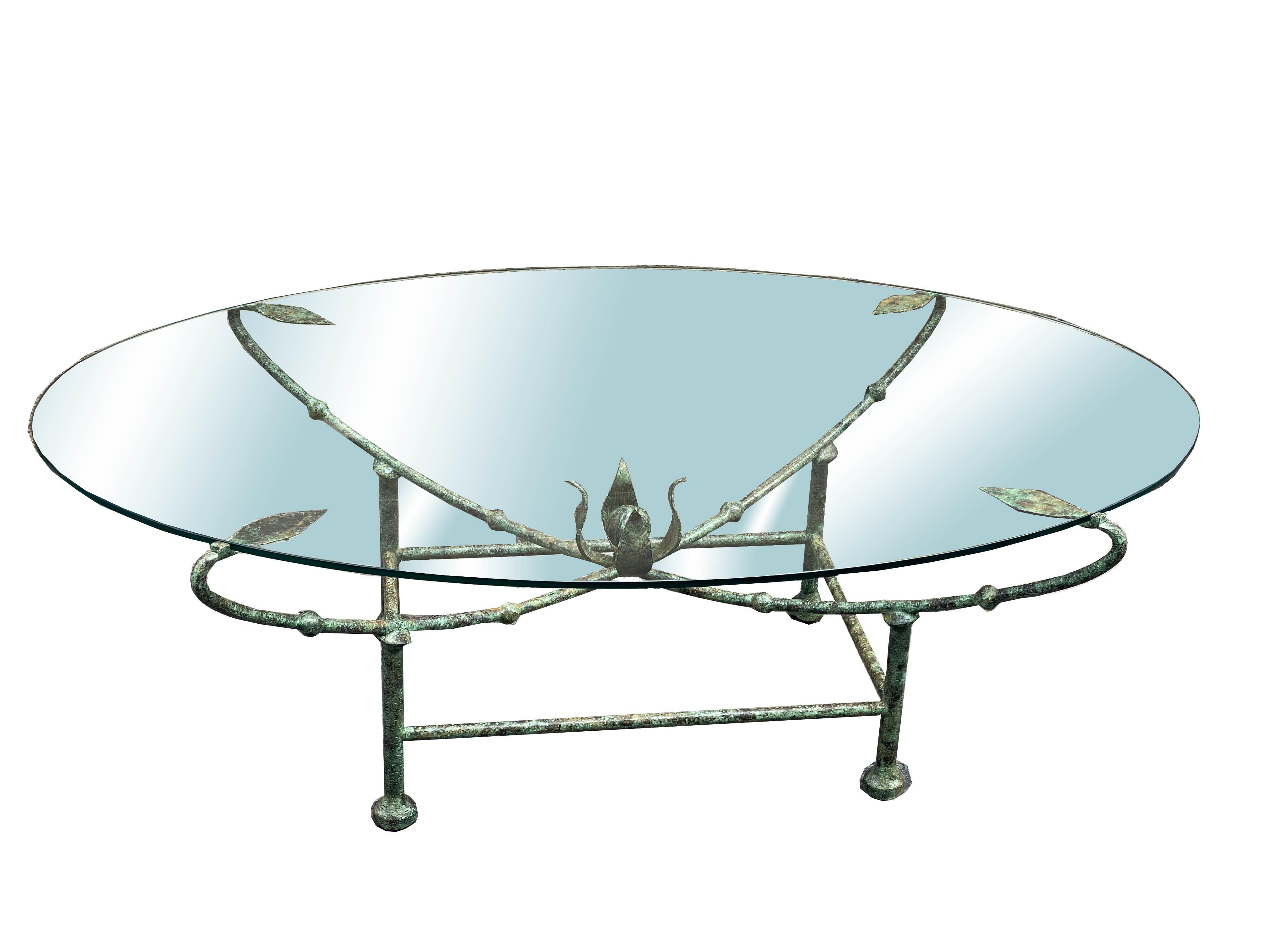 Delicate and elegant oval-shaped coffee table, the wrought iron frame supports the glass top.The wrought iron construction has four large, very decorative leaves and a central flower.