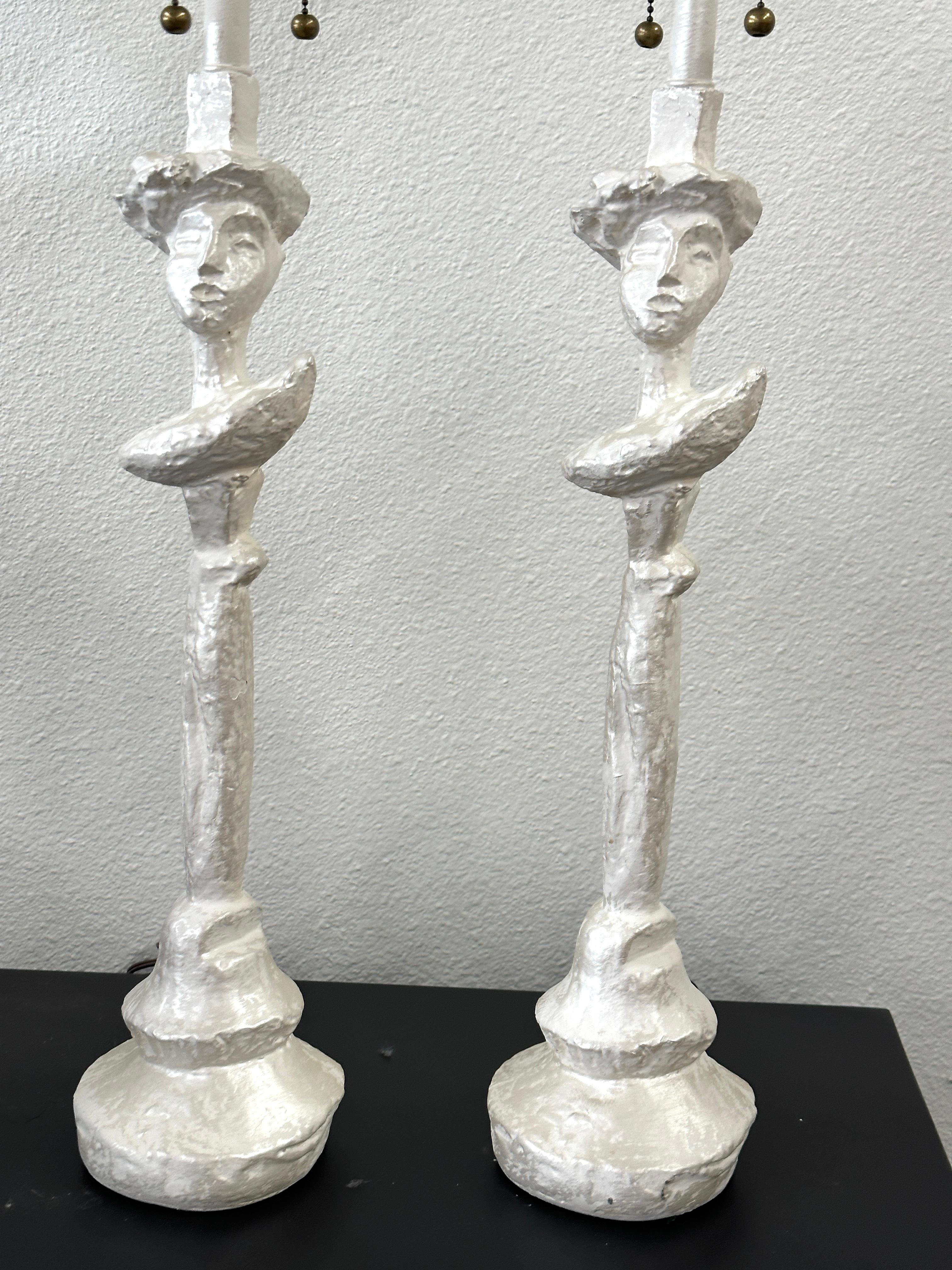 A great pair of plaster after the “Tete de Femme” lamps designed by Giacometti for Syrie Maugham in the 1930’s. These lamps look to be from the 1960’s based on the wiring and electrical fixtures.  We’ve pictured the original as found cords ands