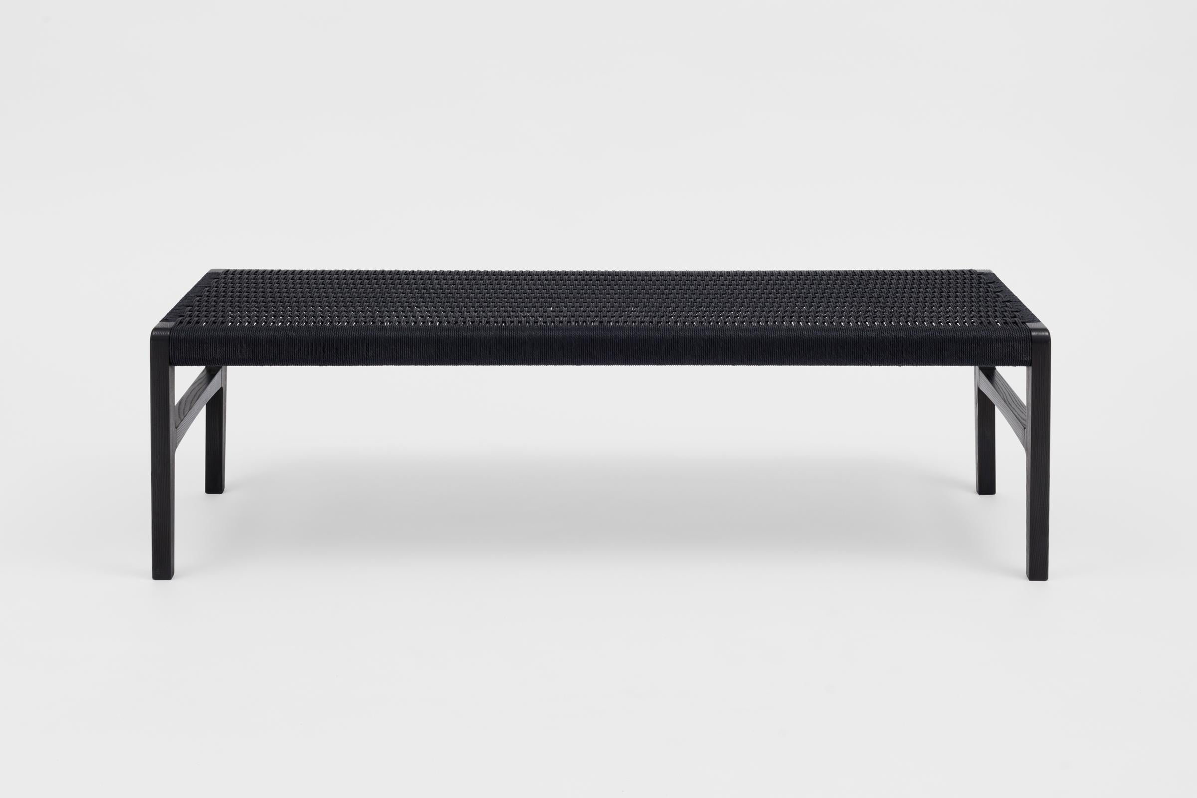 A bench with subtle curves (shown in ebonized ash) with a woven Danish cord seat, perfect for use in the bedroom, hallway, living space or kitchen. Measures 59”.